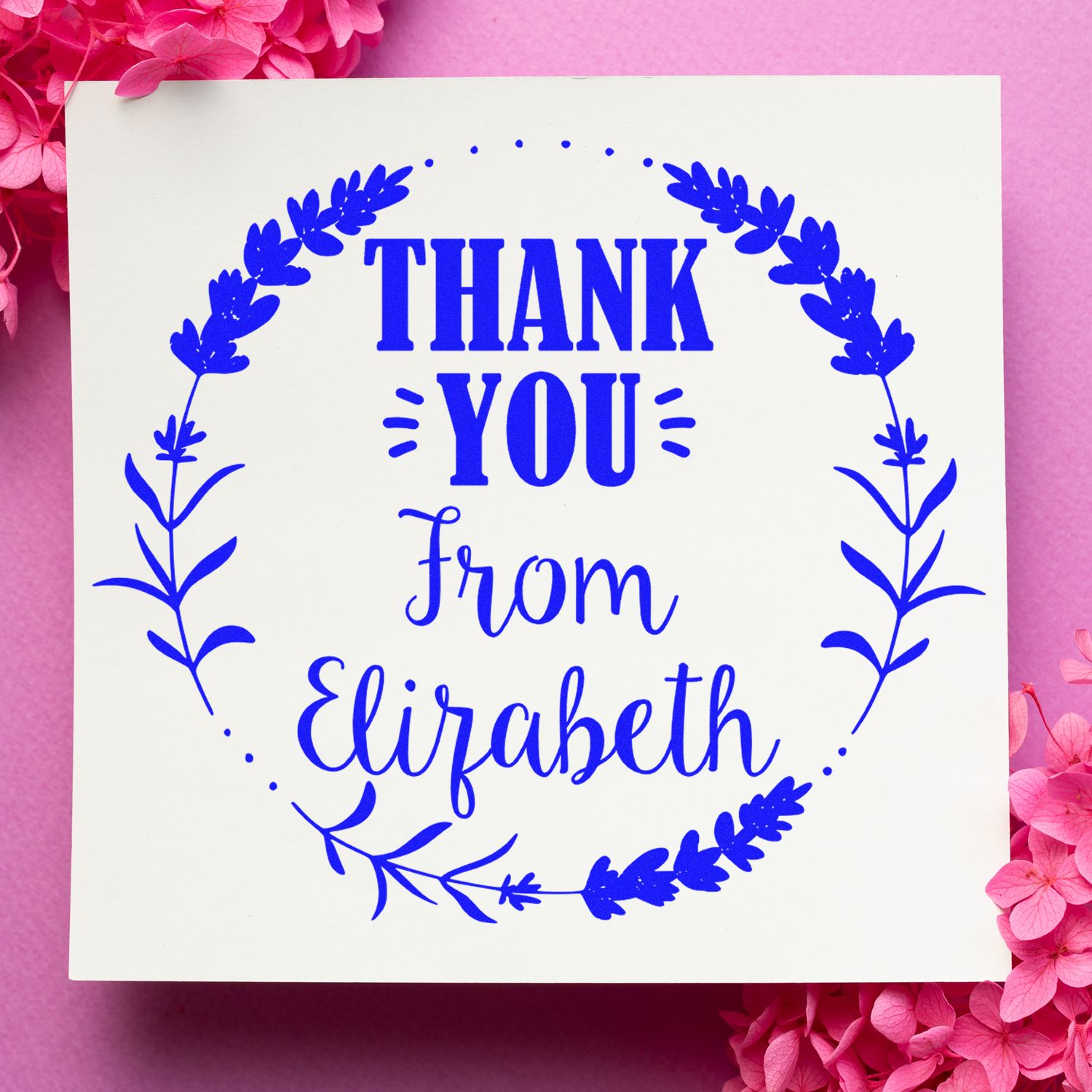 Blue thank you stamp seal with floral wreath and Elizabeth on white paper, framed by pink flowers.