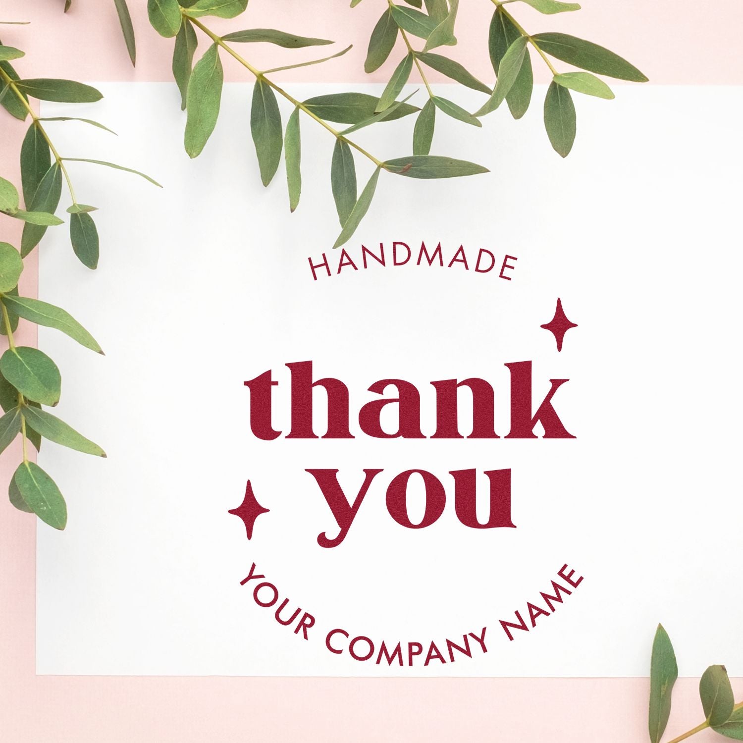 Burgundy handmade thank you stamp seal with custom company name on white card, framed by green eucalyptus leaves.