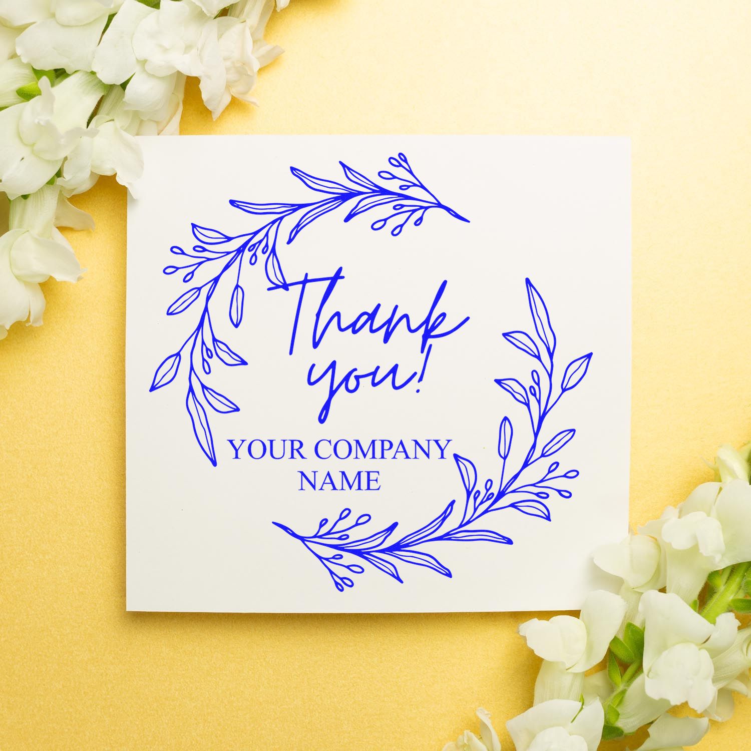 Blue thank you stamp seal with floral wreath on white card, set on gold background with white flowers.