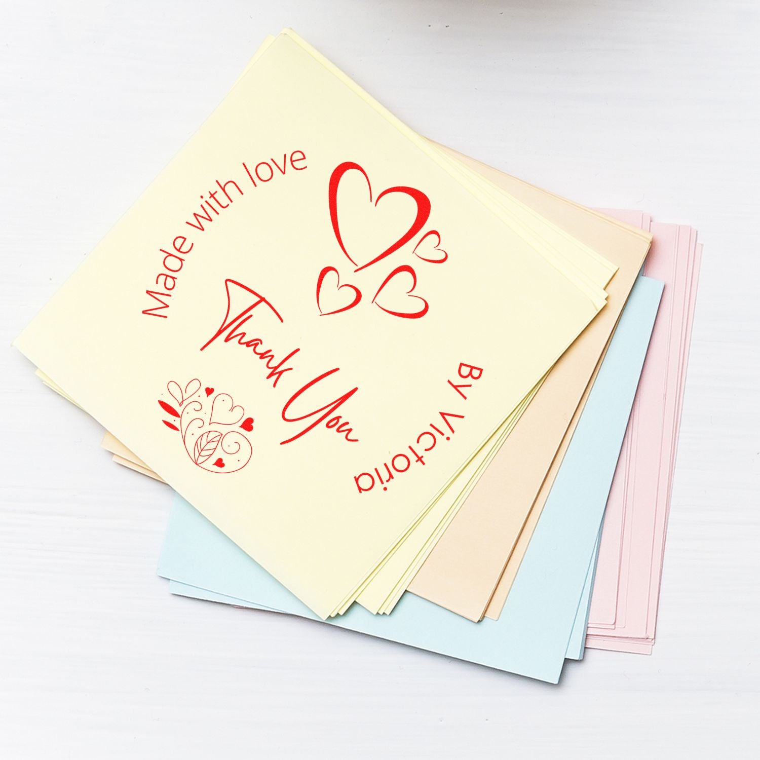 Stacked pastel stamp and seal sample sheets with red heart graphics and thank-you text on cream, blue, and pink paper.