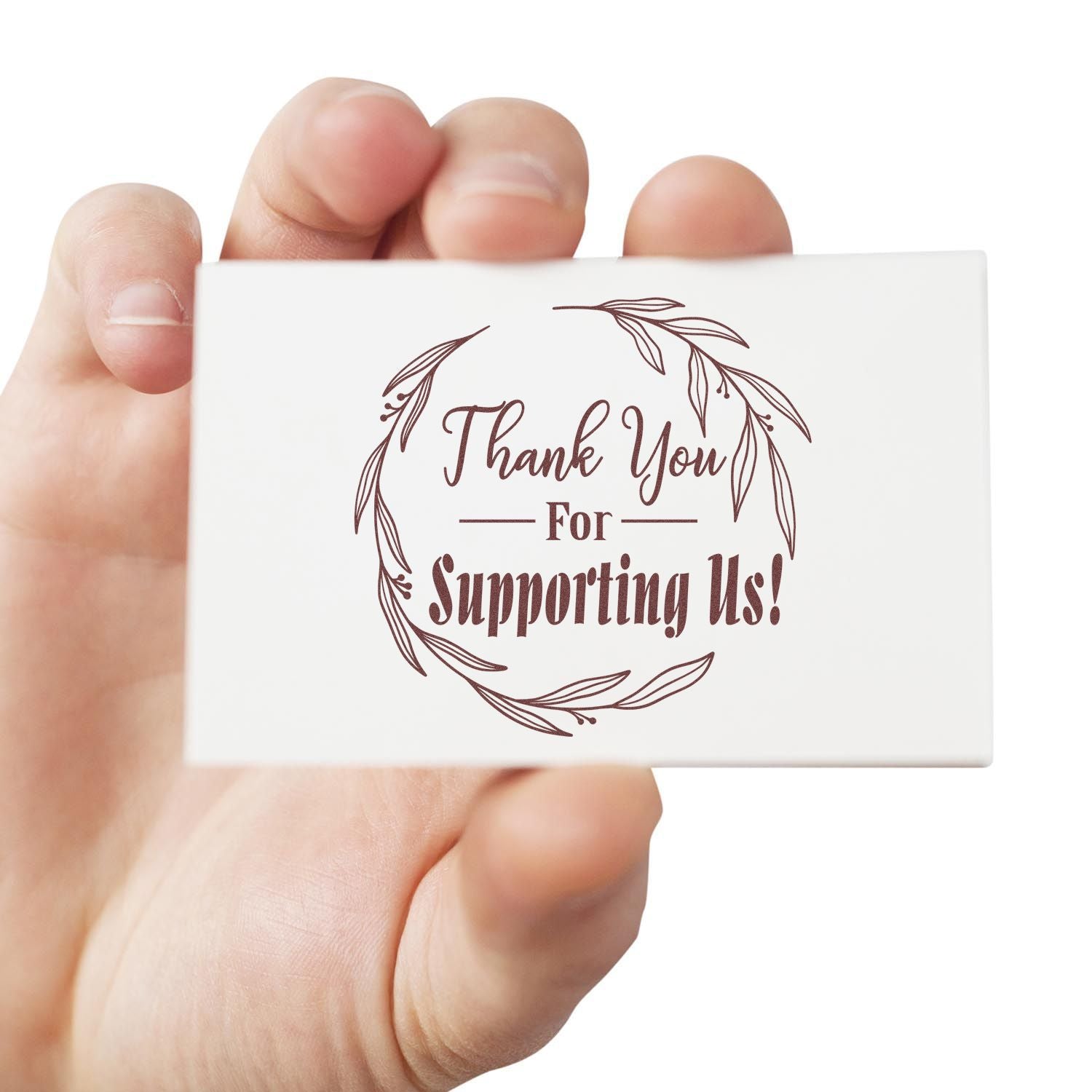 White custom stamp seal with brown floral wreath and Thank You For Supporting Us! text, held in hand.
