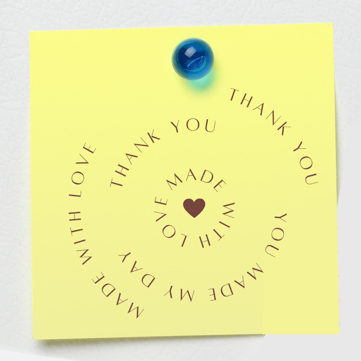 Yellow thank-you card featuring a blue seal stamp, spiral brown lettering, and a heart with made with love.