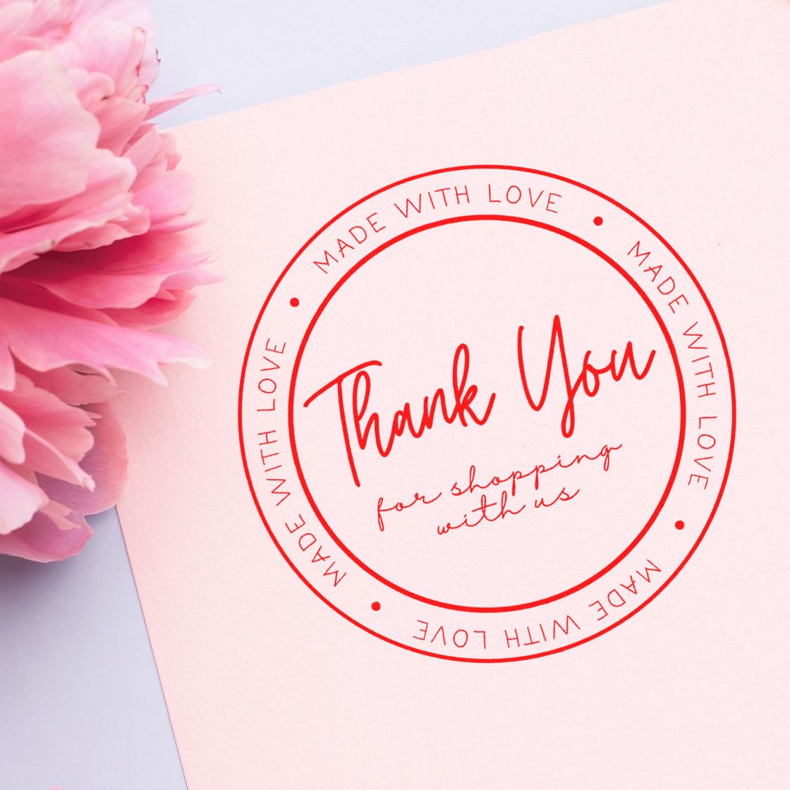 Red thank-you stamp seal on pale pink paper with pink flowers and circular Made with Love text.