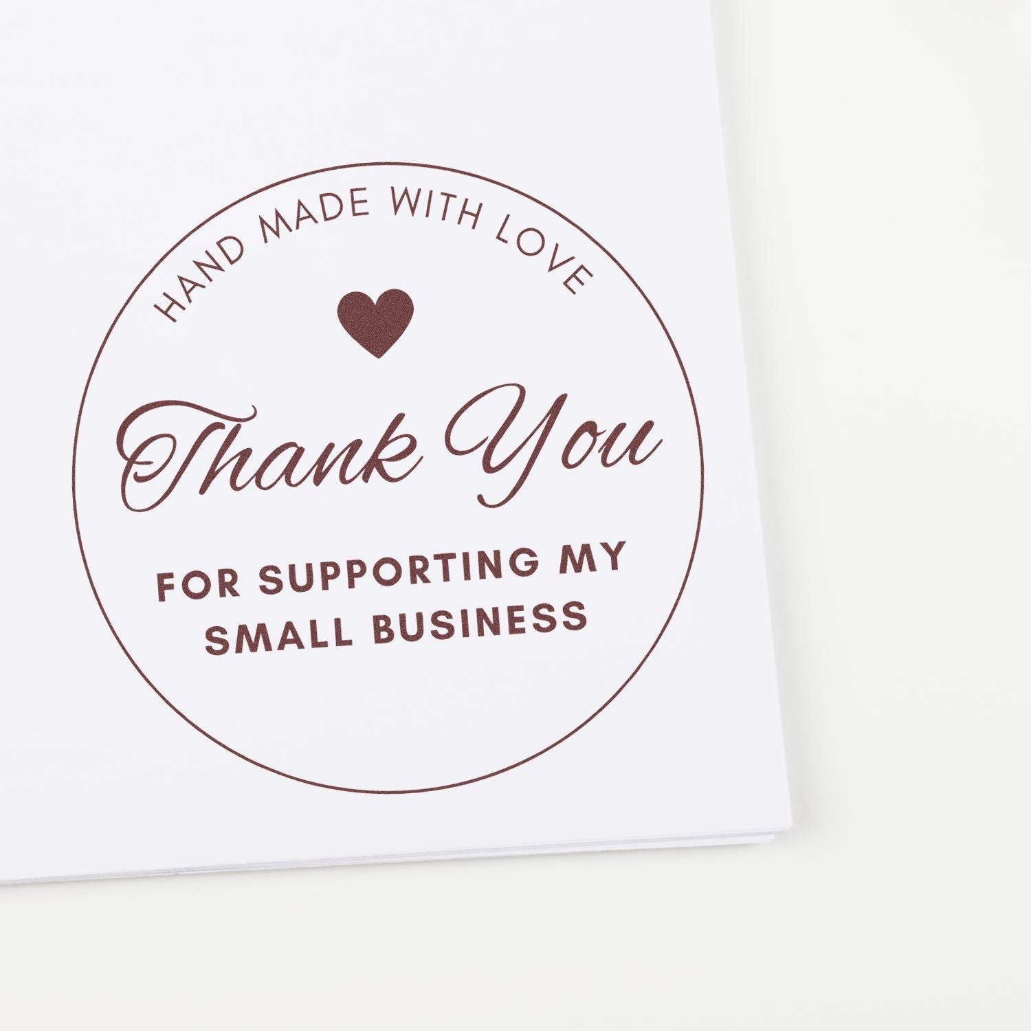 Brown circular thank-you stamp seal with heart and Hand made with love for supporting my small business on white paper.