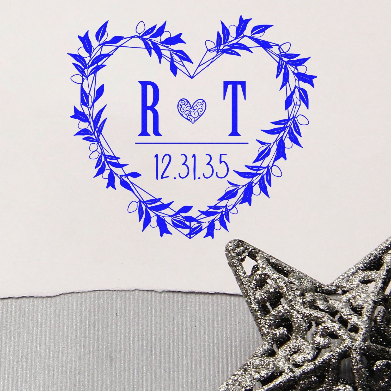 Blue heart-shaped wedding stamp with leafy wreath, R?T and 12.31.35, with a silver glitter star seal.