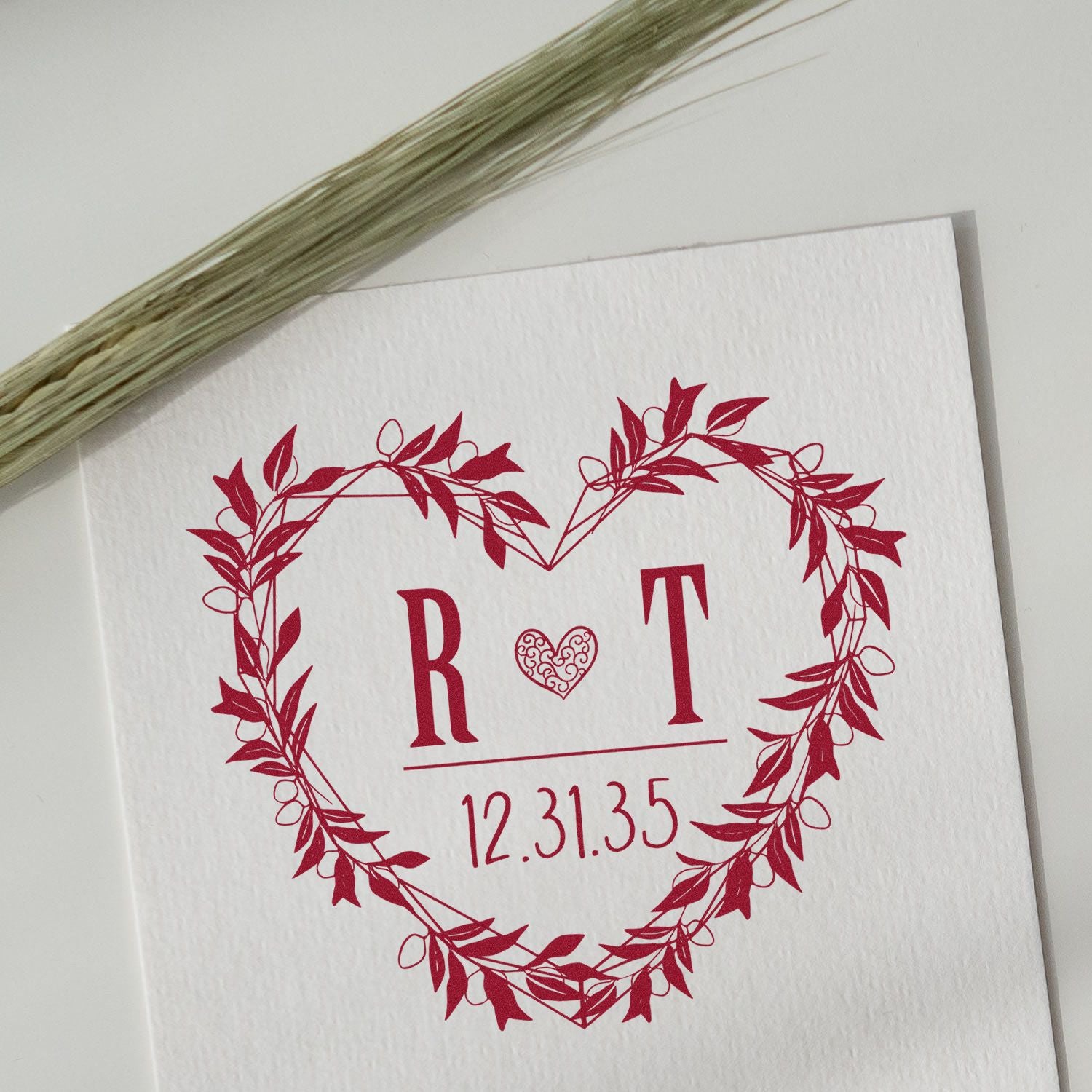 Red custom stamp seal with heart wreath, initials R ? T, and date 12.31.35 on white textured card