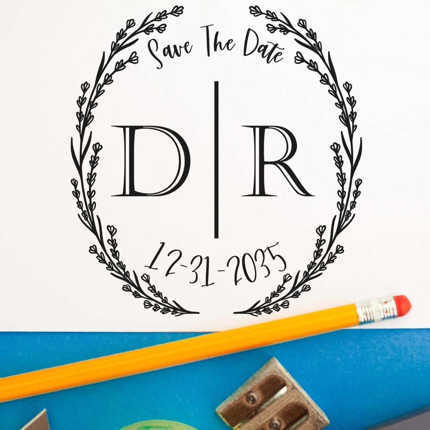 Black save-the-date stamp seal with floral wreath, D|R initials, and 12-31-2035 on white paper.