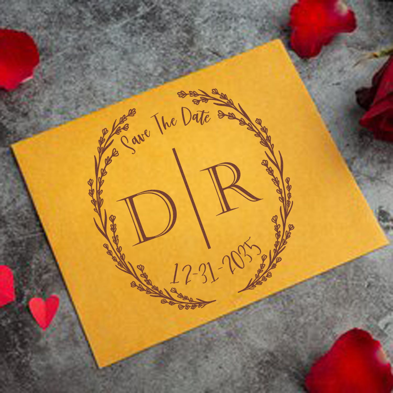 Brown wedding save-the-date stamp seal on golden-yellow card with floral wreath and 12-31-2035, on gray background with red petals.