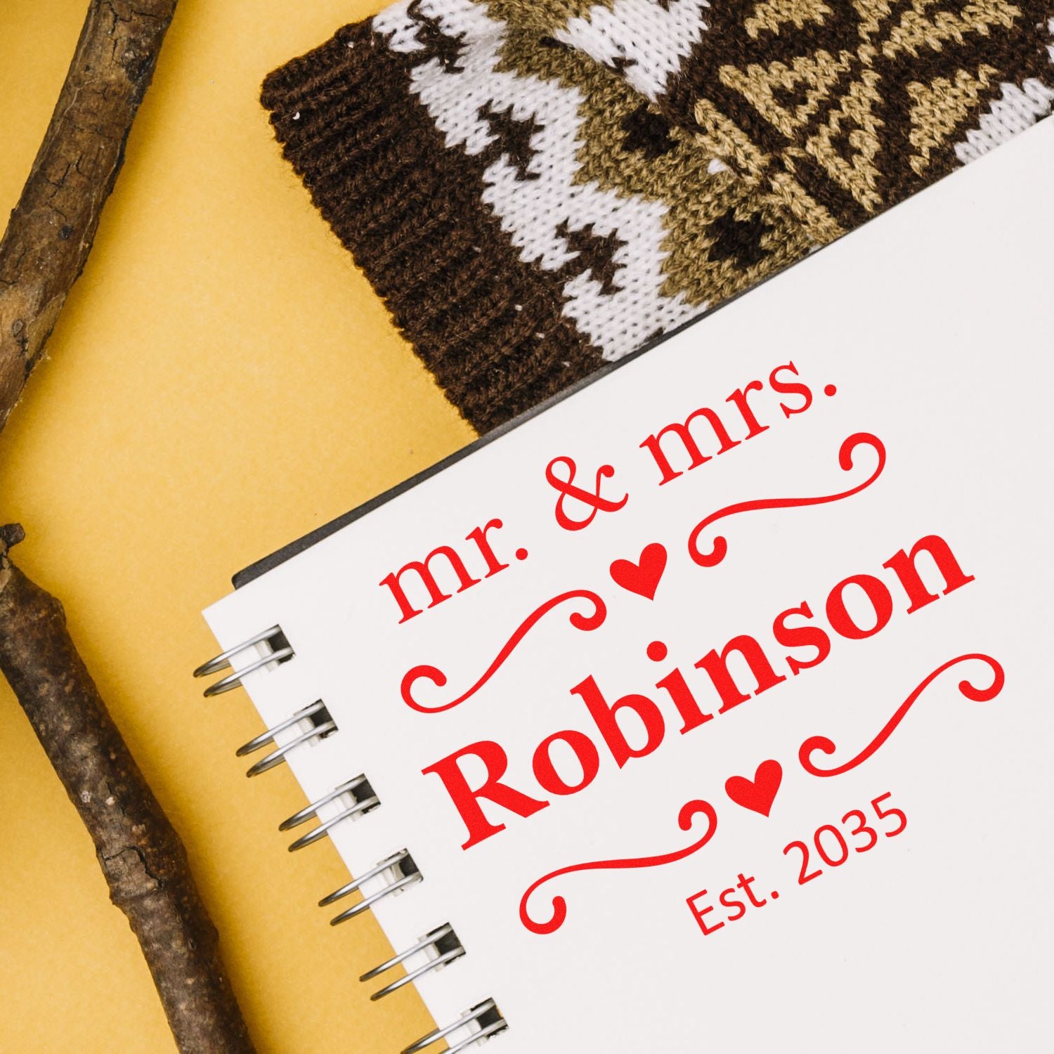 Custom red wedding stamp and seal on white notebook, reading "mr. & mrs. Robinson Est. 2035" with heart accents.
