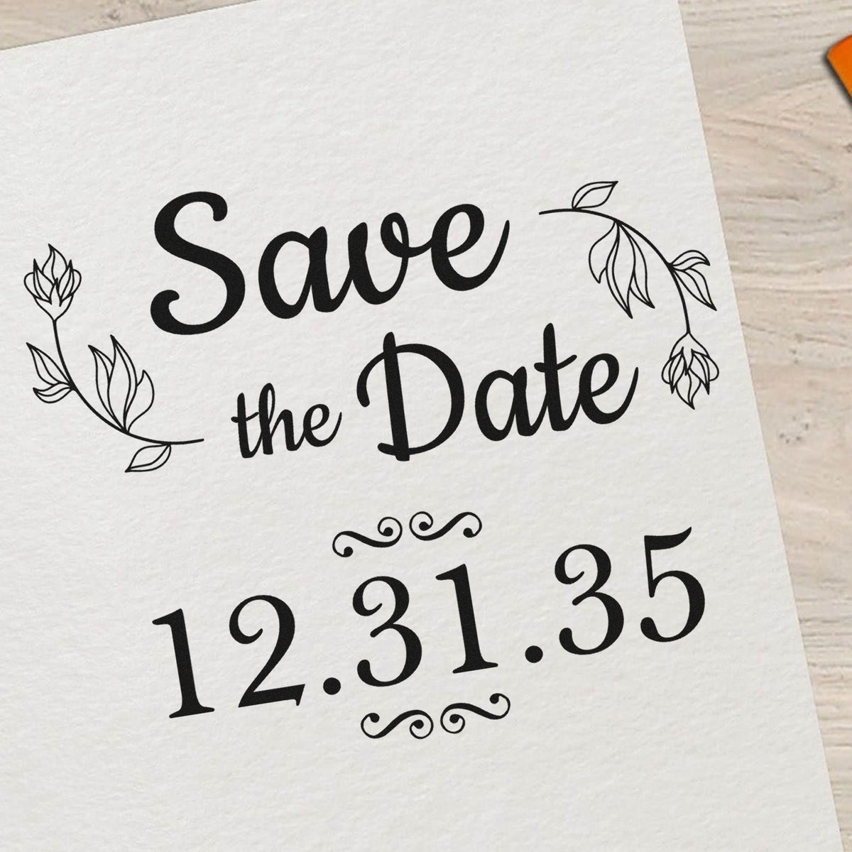 Black Save the Date stamp/seal with floral line art and date 12.31.35 on white paper