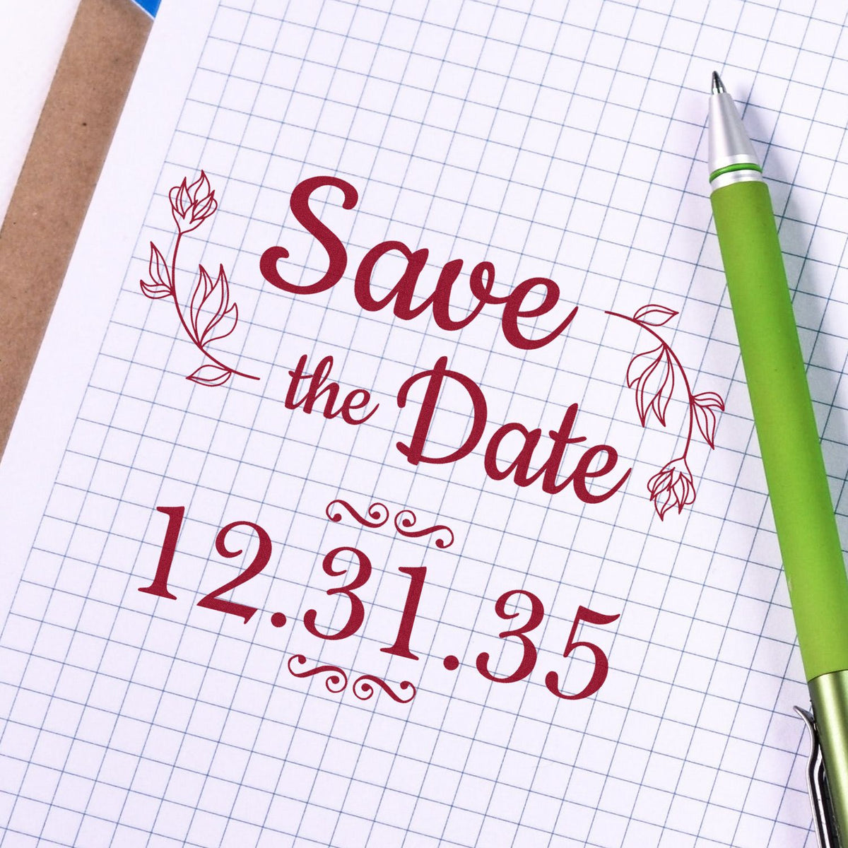 Red decorative stamp seal on graph paper reads Save the Date 12.31.35, with floral accents and a green pen.