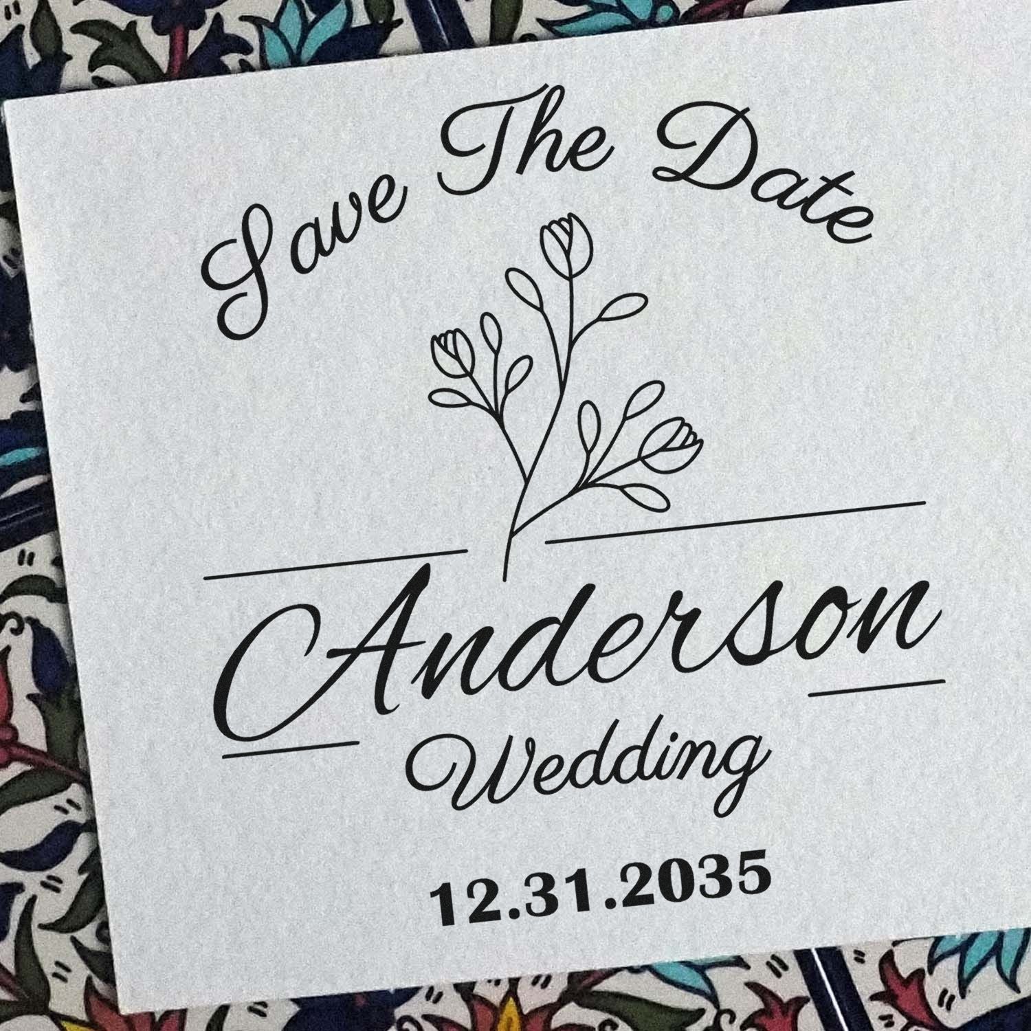 Black wedding stamp and seal on white paper with floral sprig, Love The Date Anderson Wedding, and date 12.31.2035.