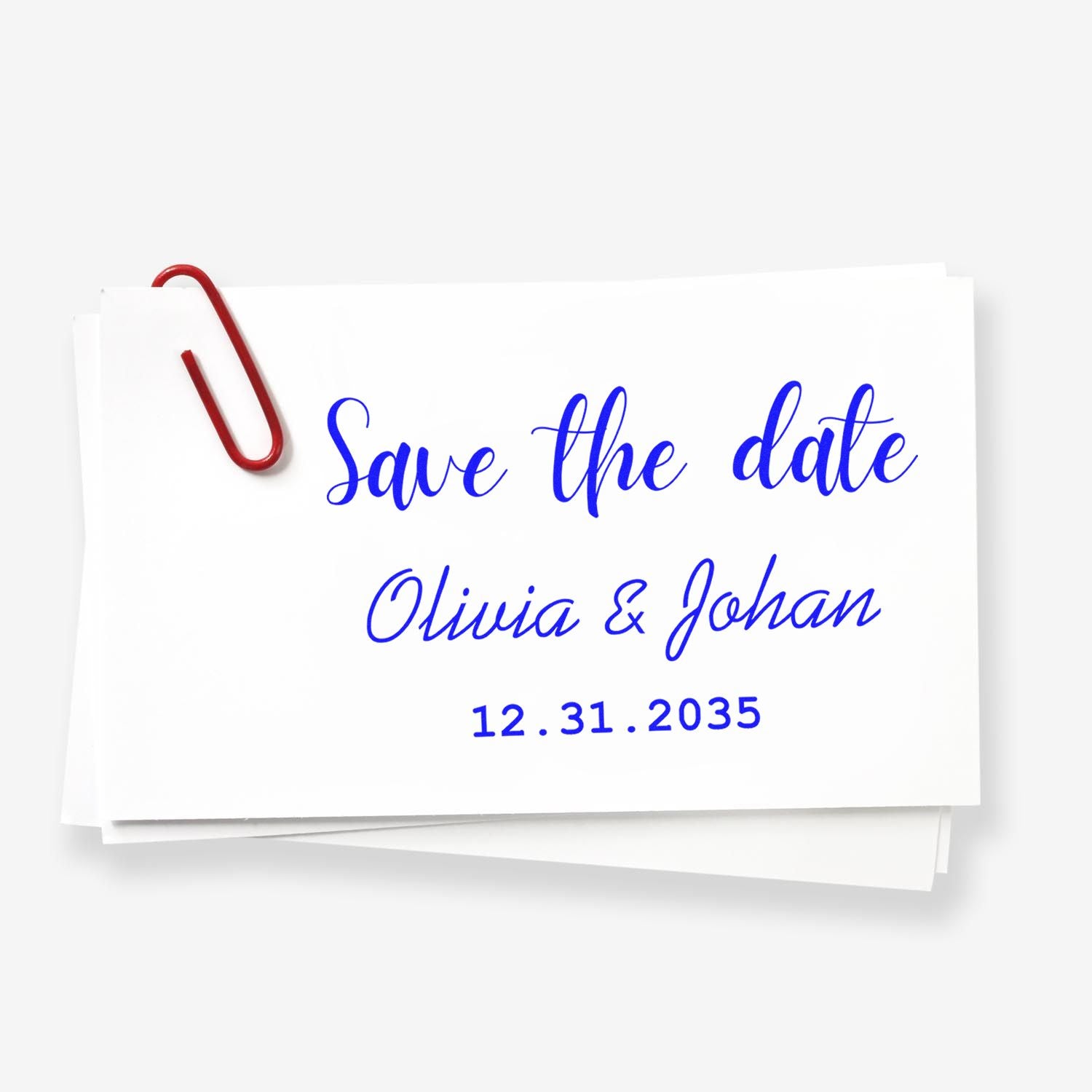 Blue save-the-date stamp on stacked white cards, with red paper clip; Olivia & Johan, 12.31.2035.