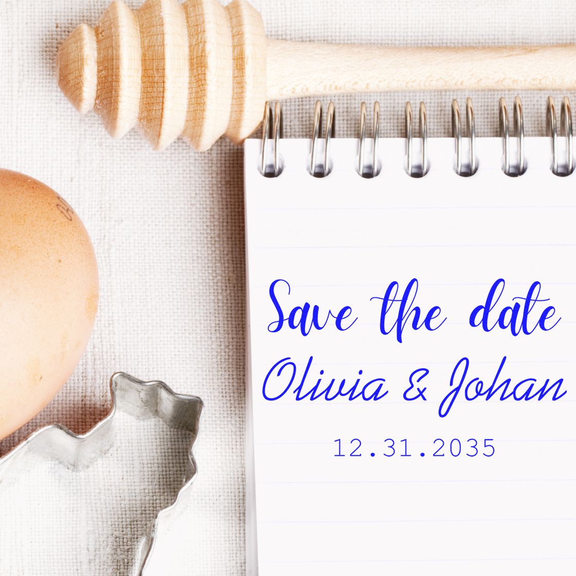 Blue save-the-date stamp and seal mockup on a white notepad, with Olivia & Johan, wooden stamp, egg, and metal cutter.