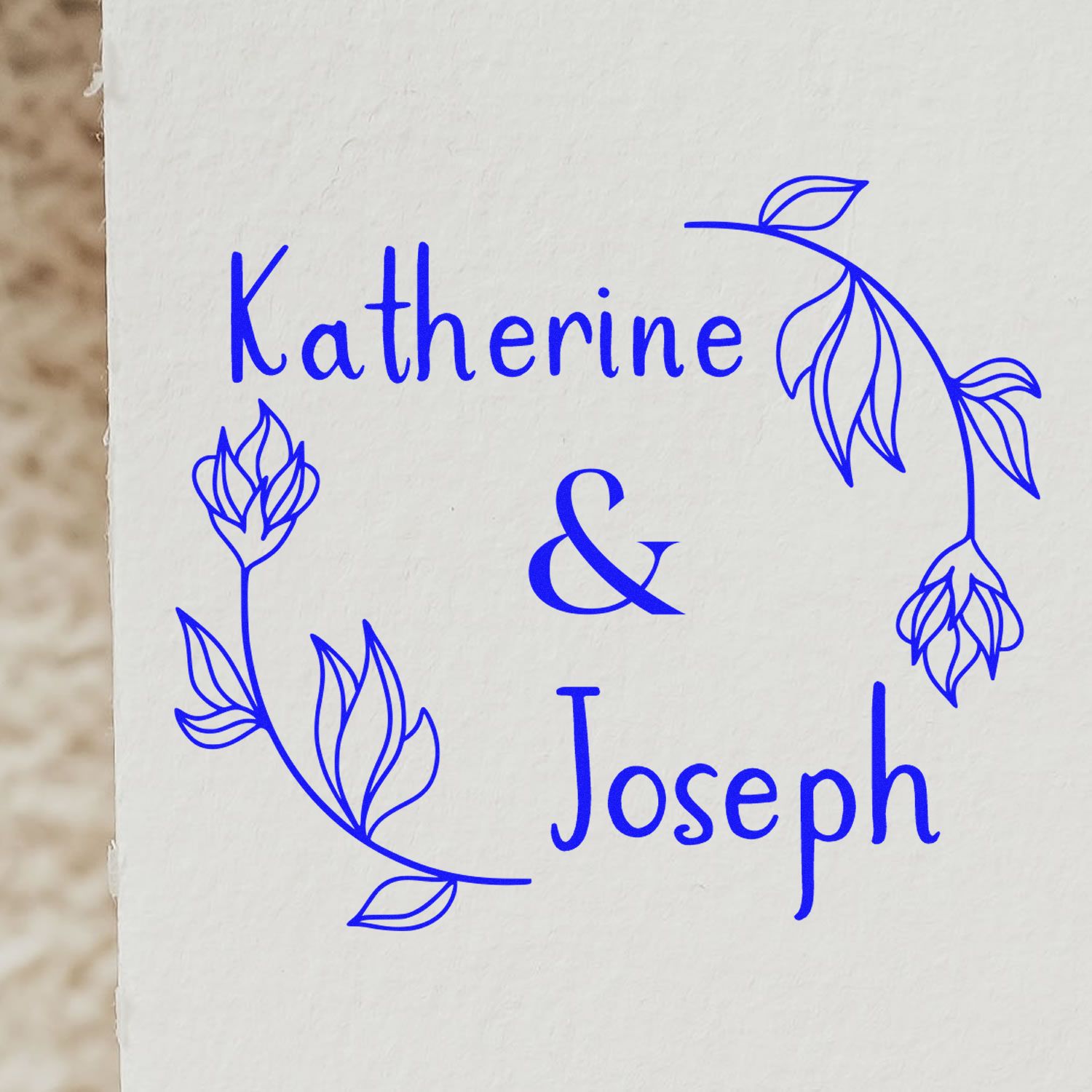 Blue custom stamp seal with floral wreath and Katherine & Joseph names on white paper.