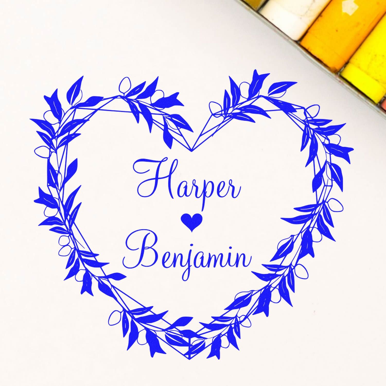Blue custom stamp seal with leafy heart wreath, Harper and Benjamin names, and a small heart on white background.
