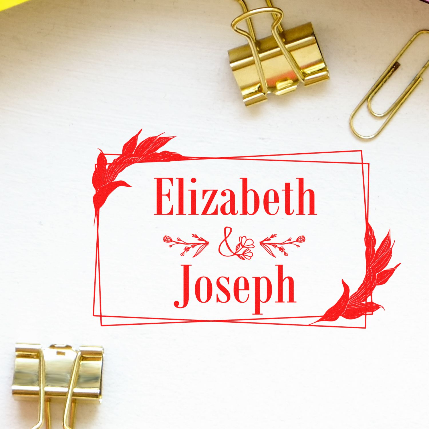 Red custom stamp seal reading Elizabeth & Joseph with floral frame, on white paper, accented by gold binder clips.