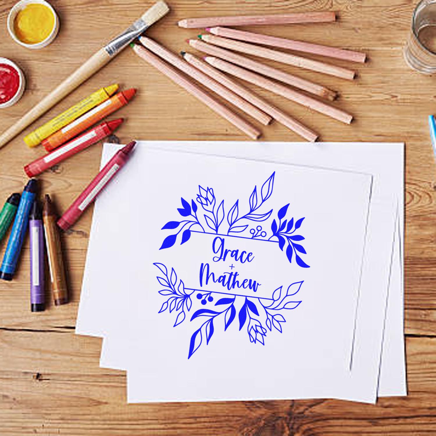 Custom blue floral stamp and seal design for Grace and Matthew on white paper, with pencils and paint on wood.
