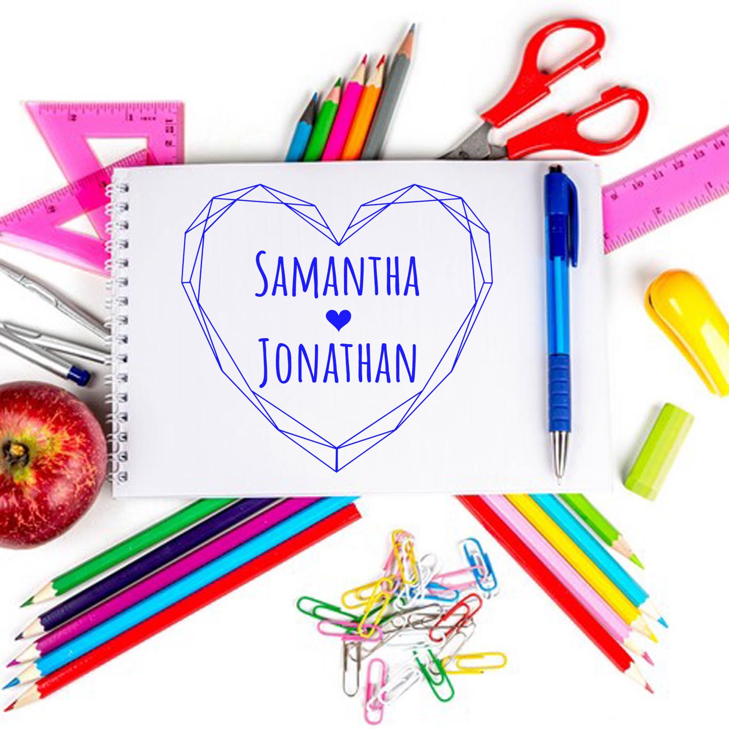 Blue heart-shaped stamp seal with Samantha and Jonathan on white paper, surrounded by colorful school supplies.