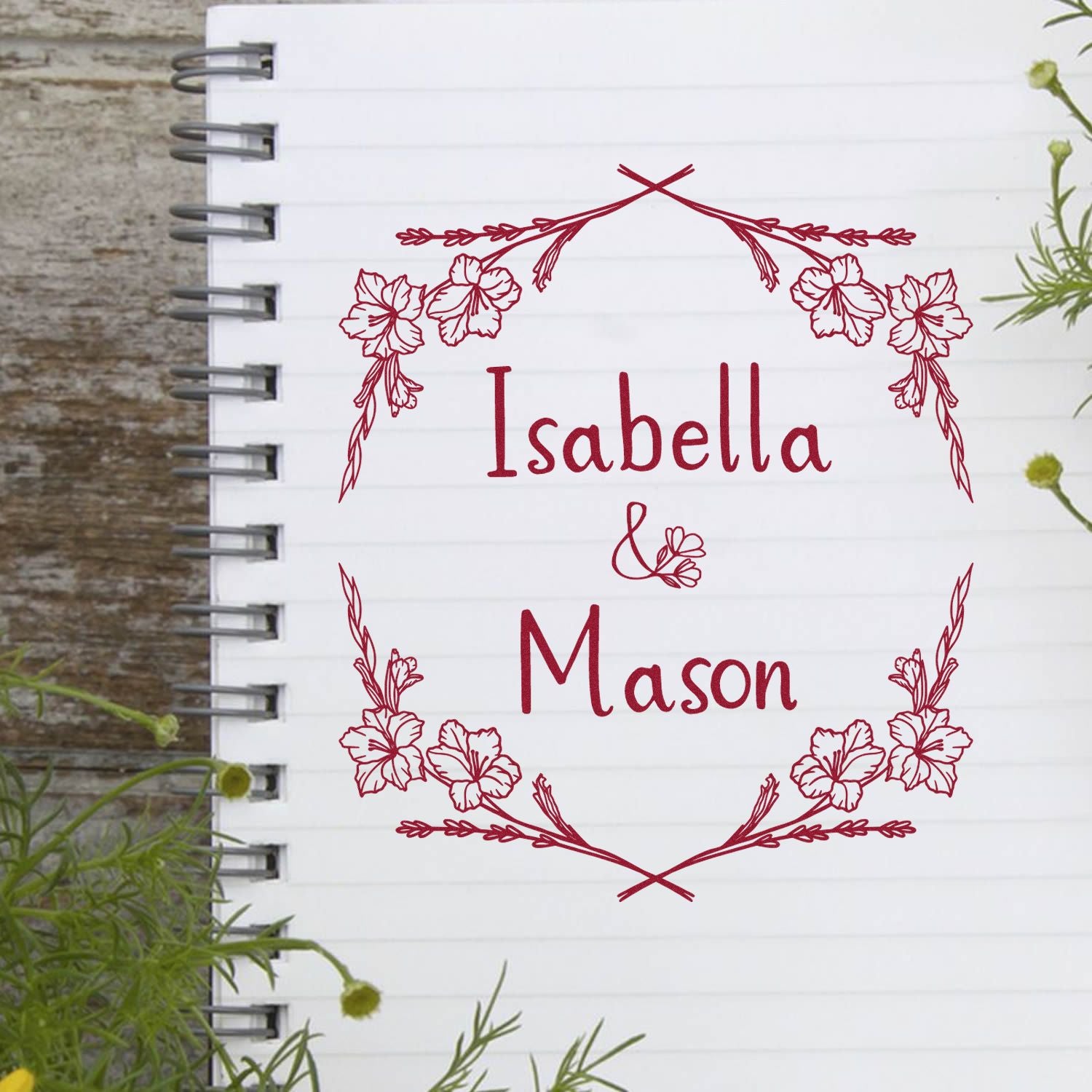 Custom red floral seal stamp reading Isabella & Mason on a white notebook page with spiral binding.