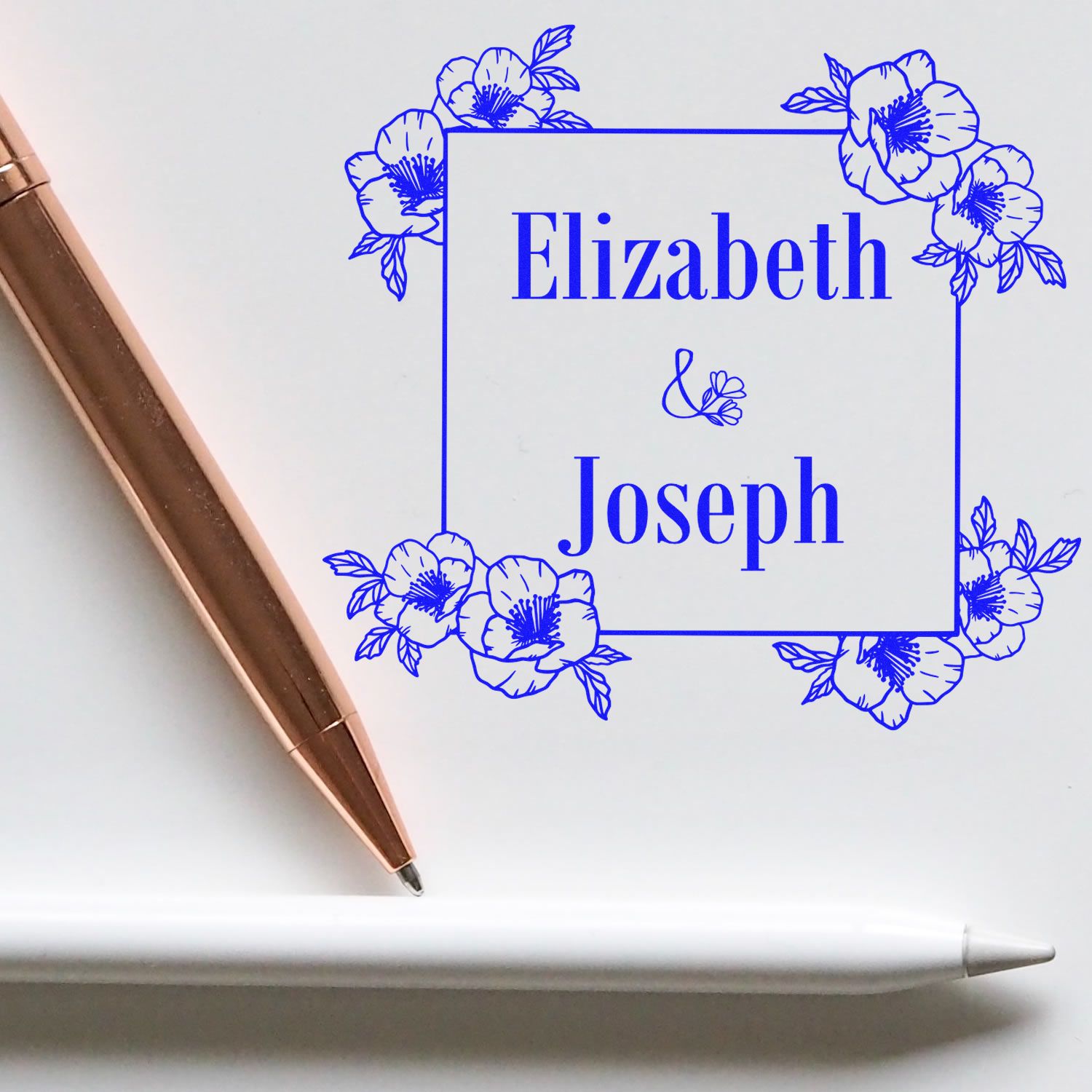 Blue floral custom stamp and seal for Elizabeth & Joseph, with rose-gold pen and white stylus on a white background.