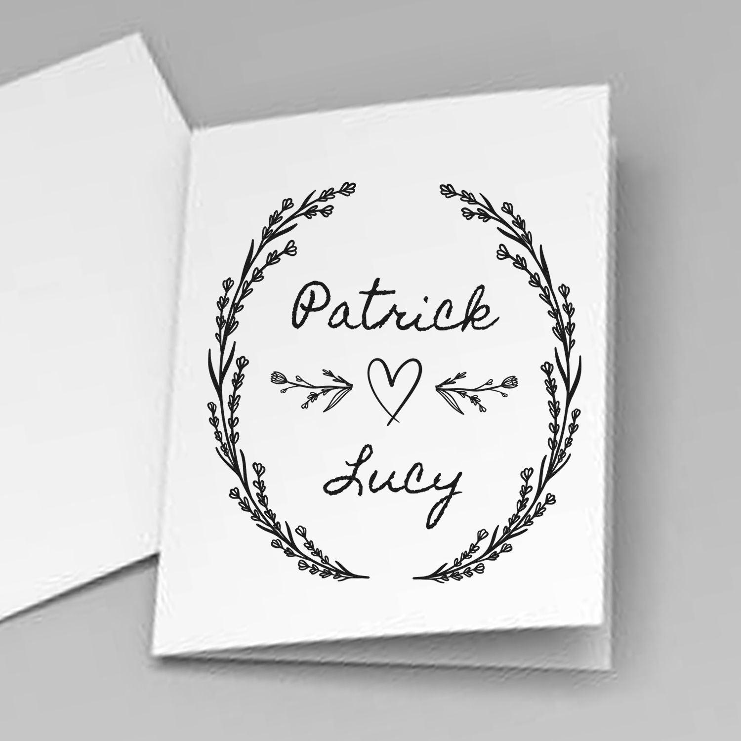 Custom black wedding stamp seal with floral wreath, heart, and names Patrick and Lucy on white card.