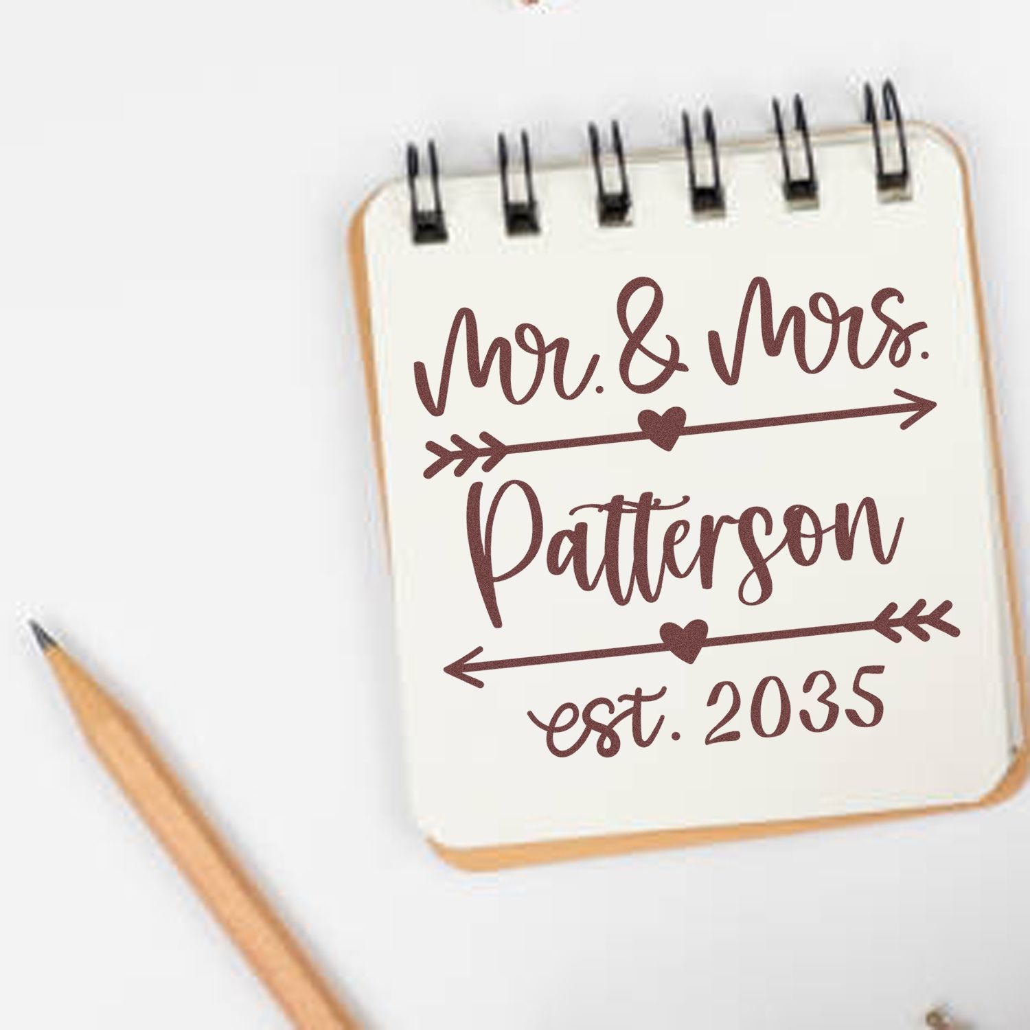 Custom wedding stamp seal in brown on cream spiral notebook: Mr. & Mrs. Patterson, arrows, hearts, est. 2035.