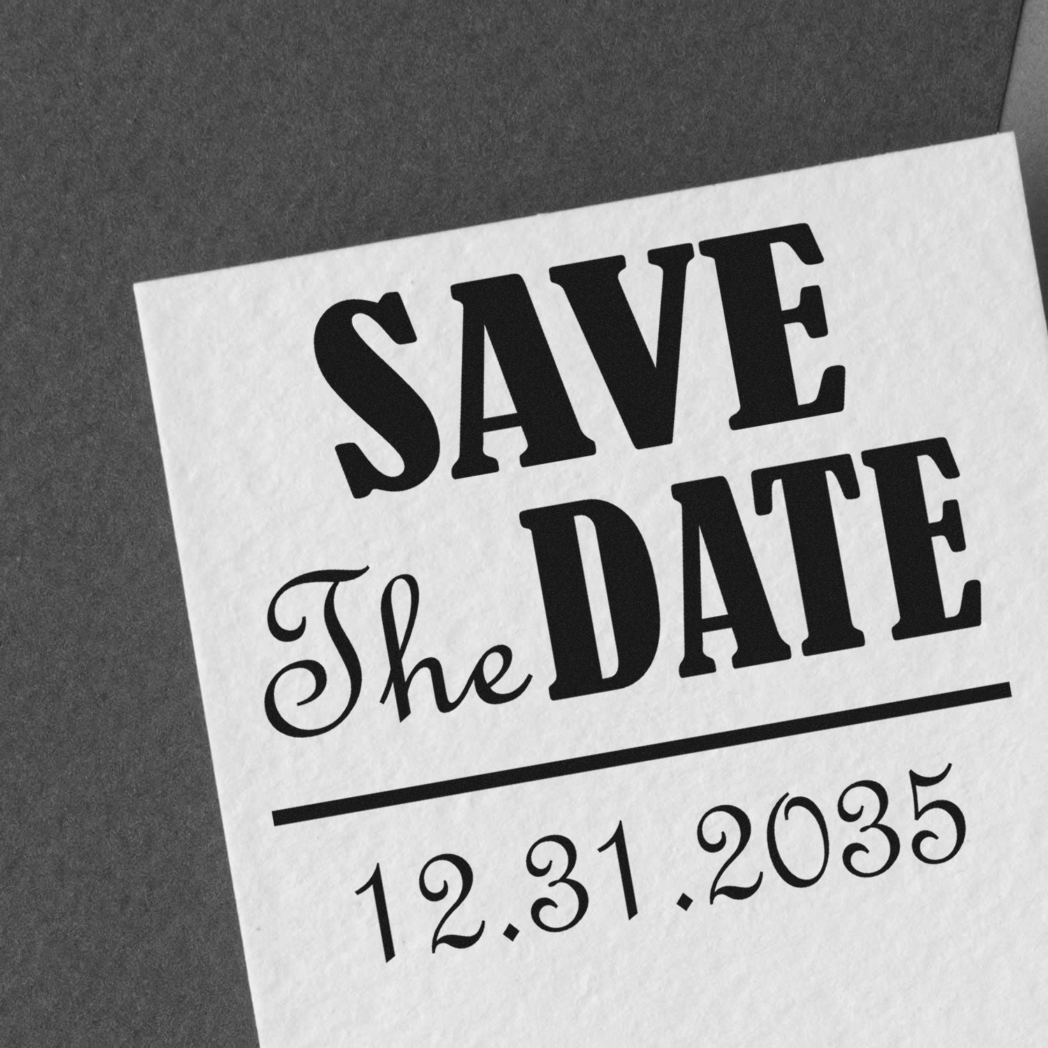 Black save-the-date stamp on white paper with The Date script and 12.31.2035 beneath a divider line.