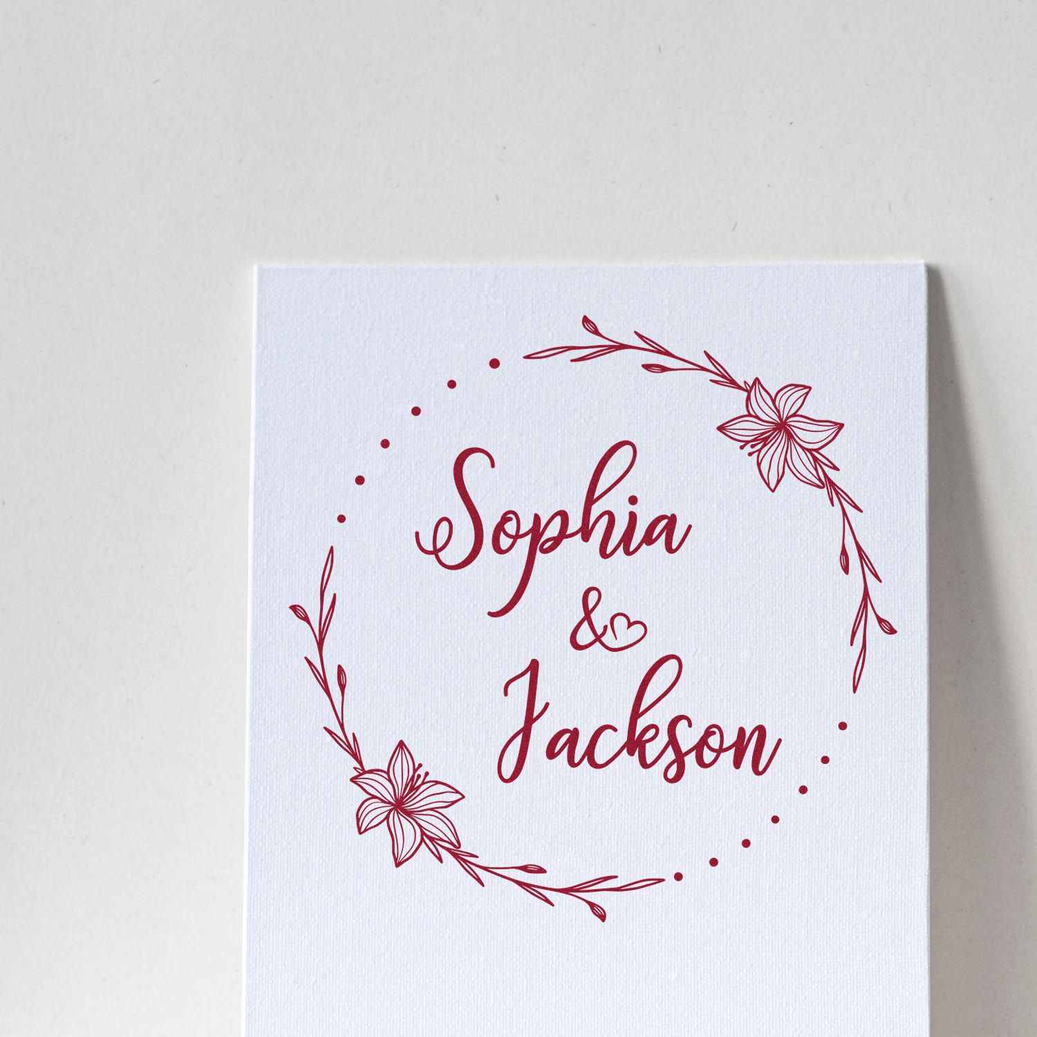 Burgundy floral wedding stamp seal on white card reading Sophia & Jackson with dotted wreath design.