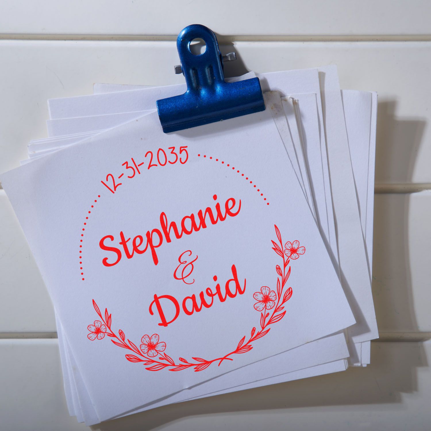 White papers clipped with blue binder clip, featuring red custom wedding stamp seal for Stephanie & David, dated 12-31-2035.