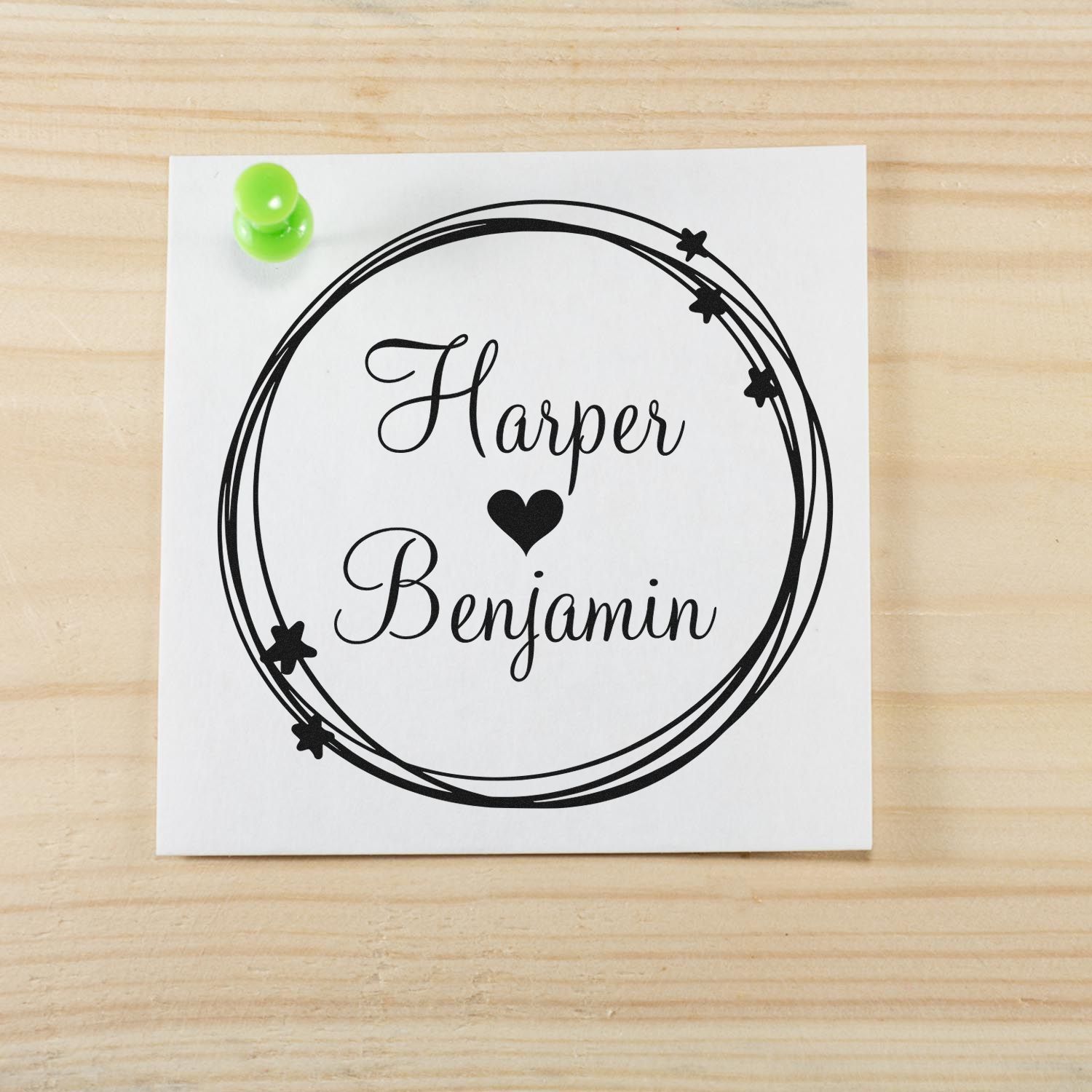 Custom black rubber stamp seal with Harper and Benjamin in script, heart and stars, on white card with green pushpin.
