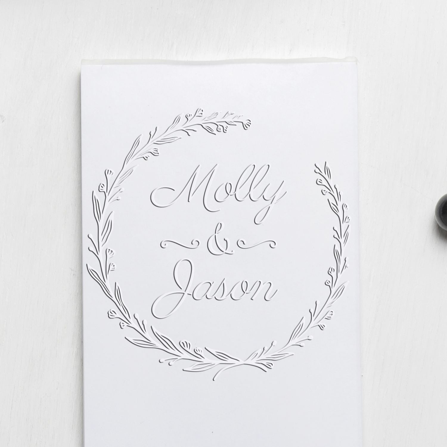 White custom embossing stamp seal with subtle silver-gray laurel wreath and Molly & Jason script on white.