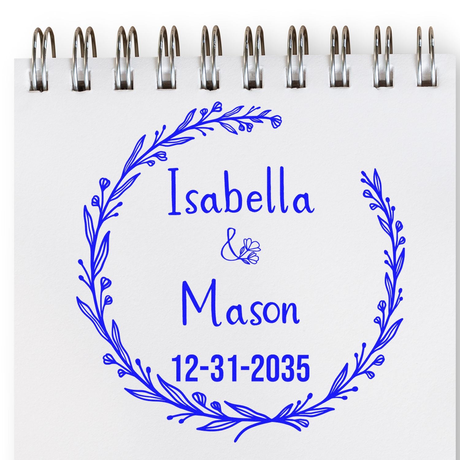 Blue floral wreath stamp seal on a spiral notebook page reading Isabella & Mason, 12-31-2035.