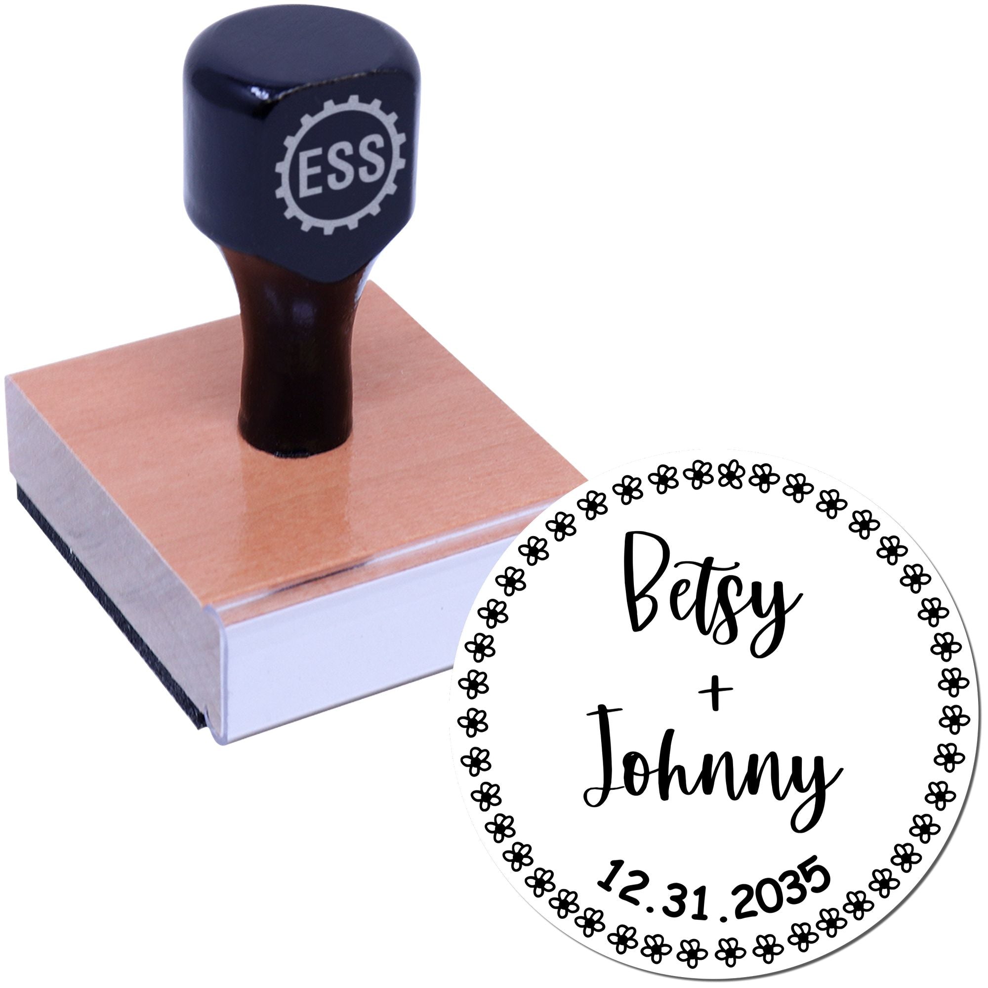 Black ESS custom stamp on pink wooden block with circular floral wedding seal reading Betsy + Johnny and 12.31.2035.