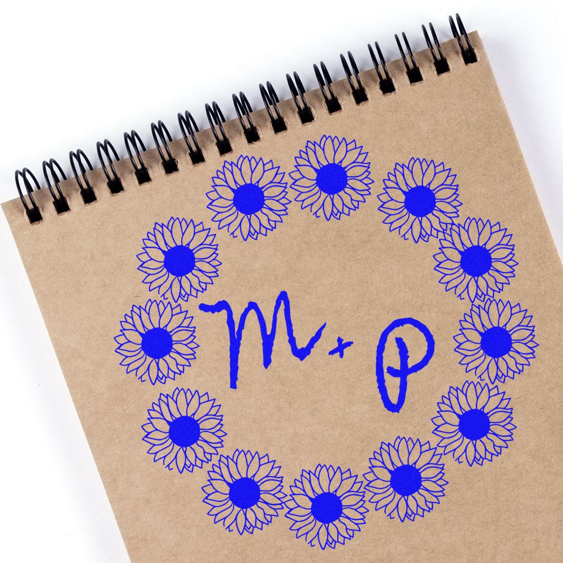 Blue floral stamp seal designs circling handwritten M + P on a kraft spiral notebook