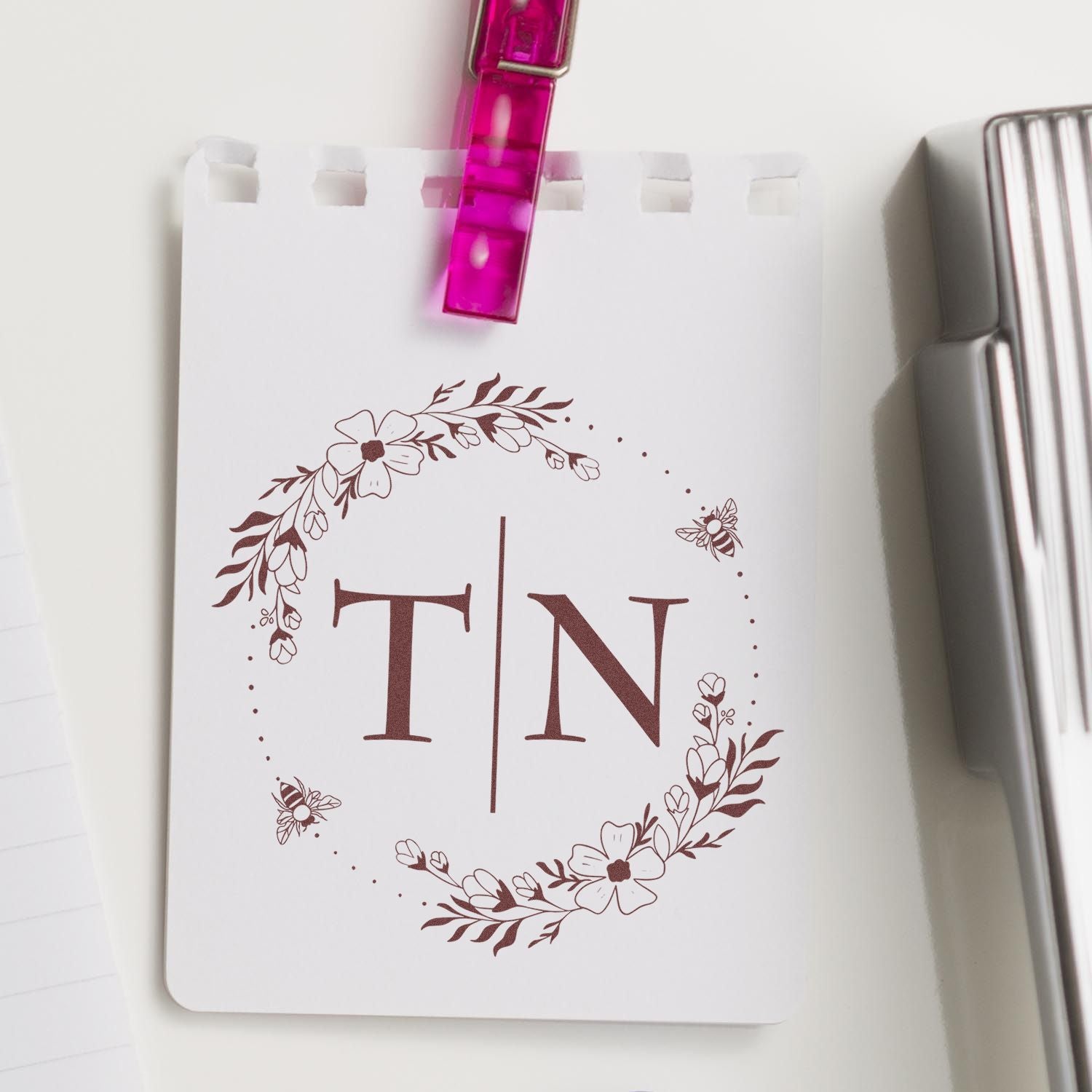 White custom stamp and seal card with brown floral TN monogram, bees, and pink clip seal.