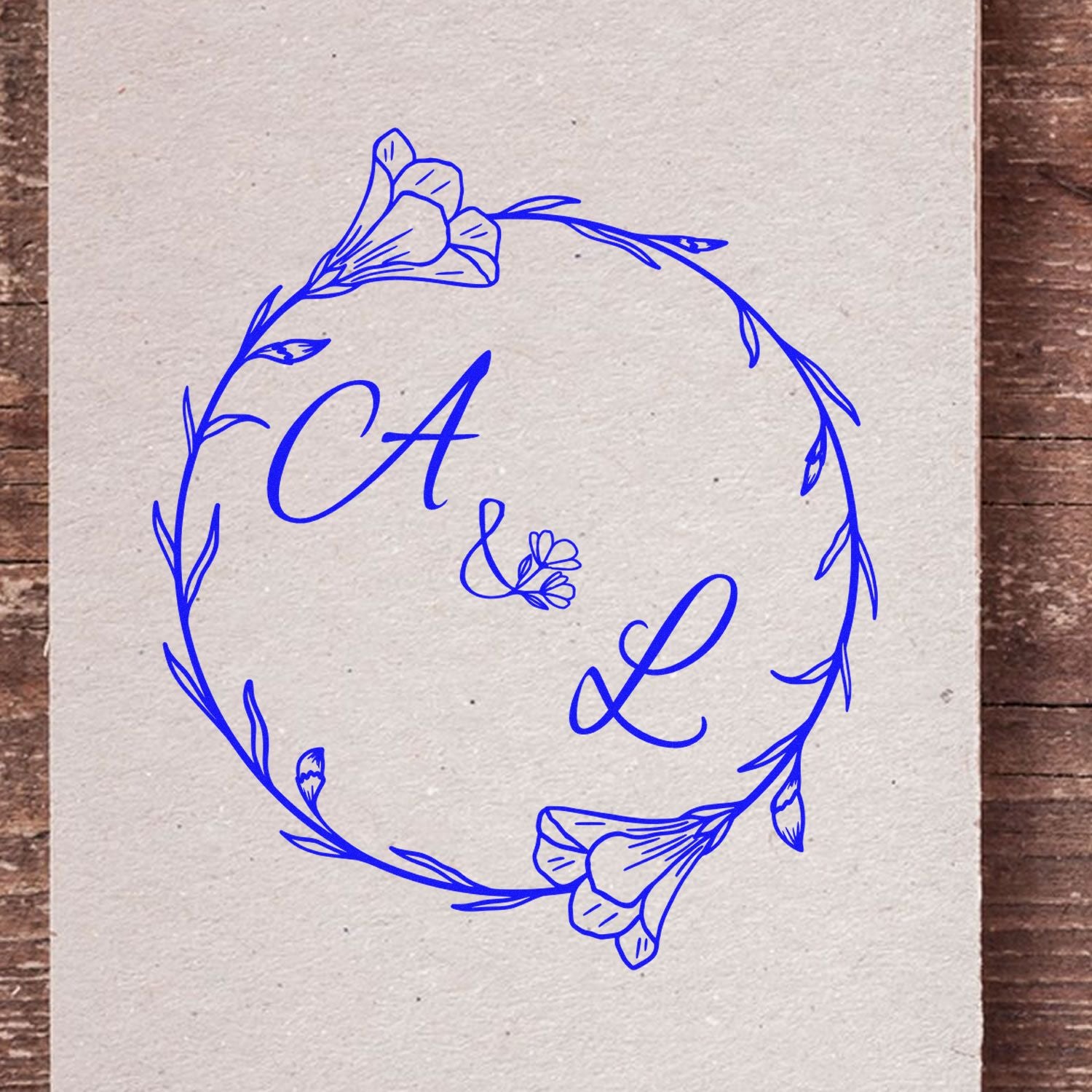 Blue floral circular monogram stamp seal with CA & L in bright blue on textured beige paper.