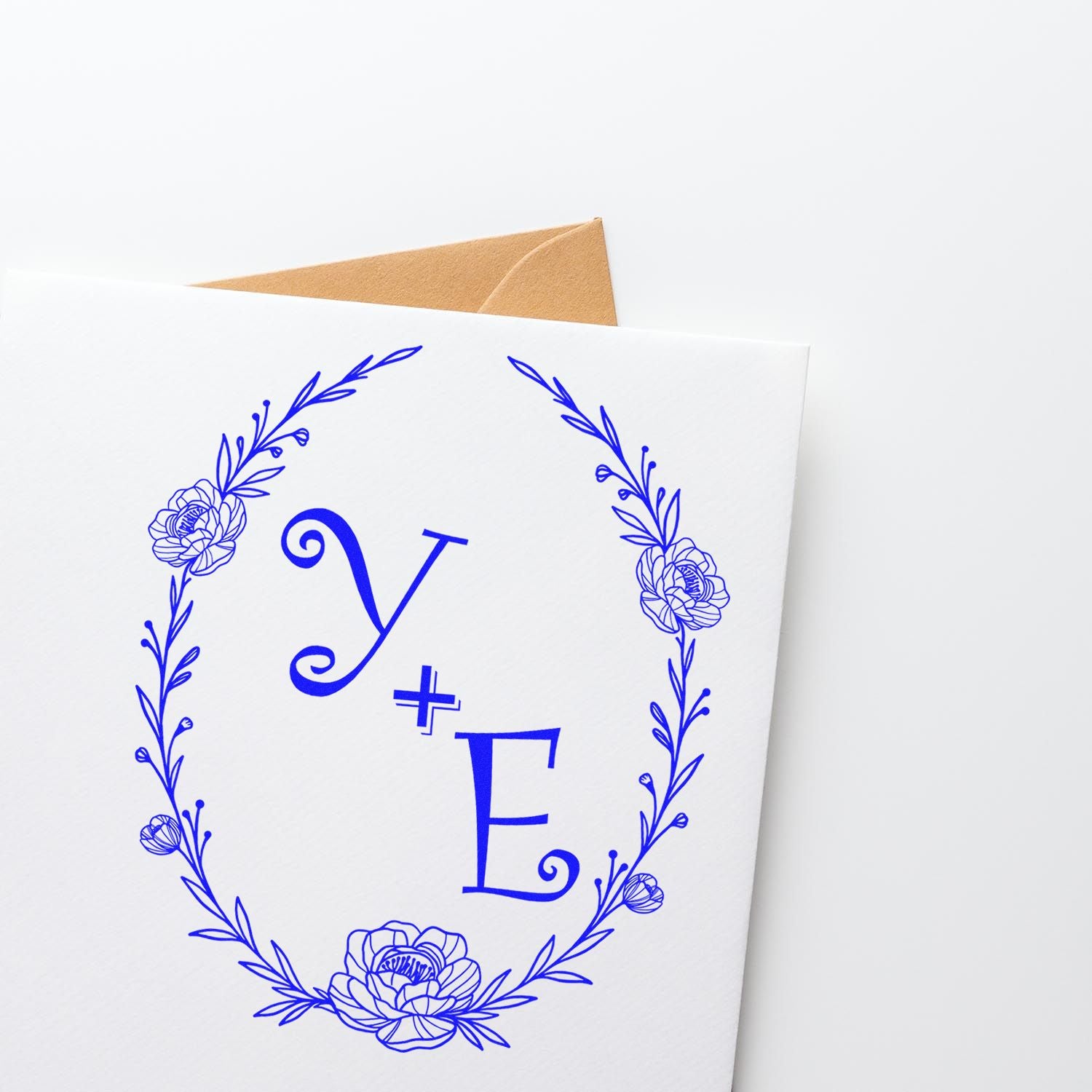Blue floral stamp and seal monogram Y+E on white card, with tan envelope peeking behind.