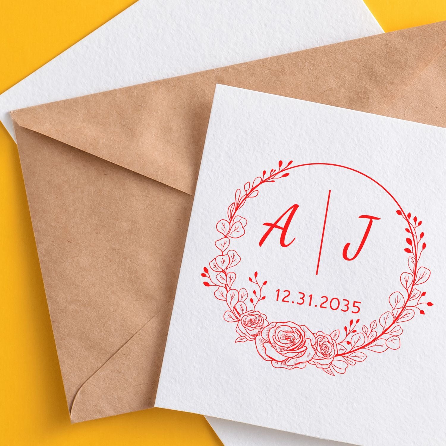 White wedding seal card with red floral monogram A | J and 12.31.2035, layered over kraft envelopes on a yellow background.