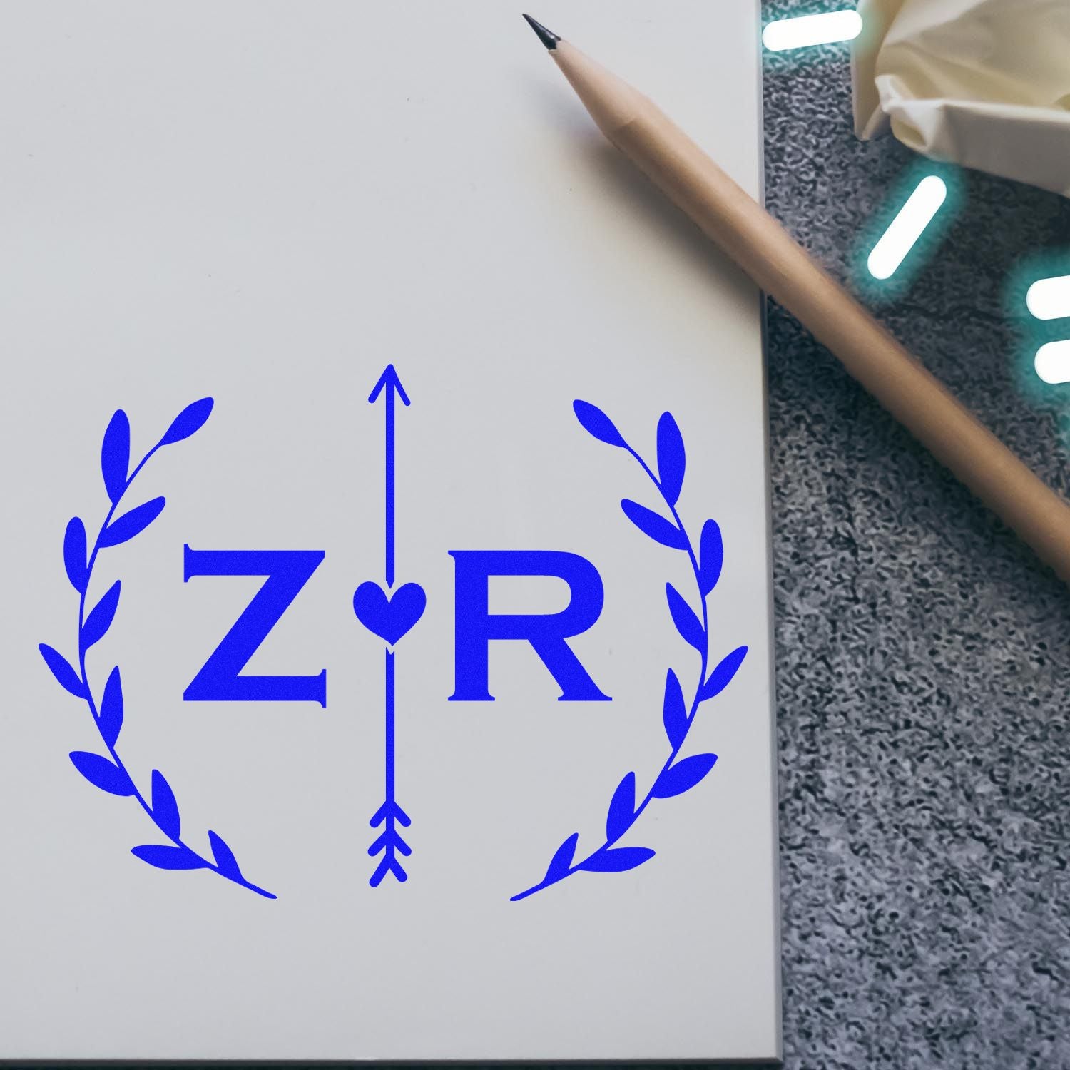Blue ZR custom stamp seal design with laurel wreath, heart arrow, and pencil on white card.