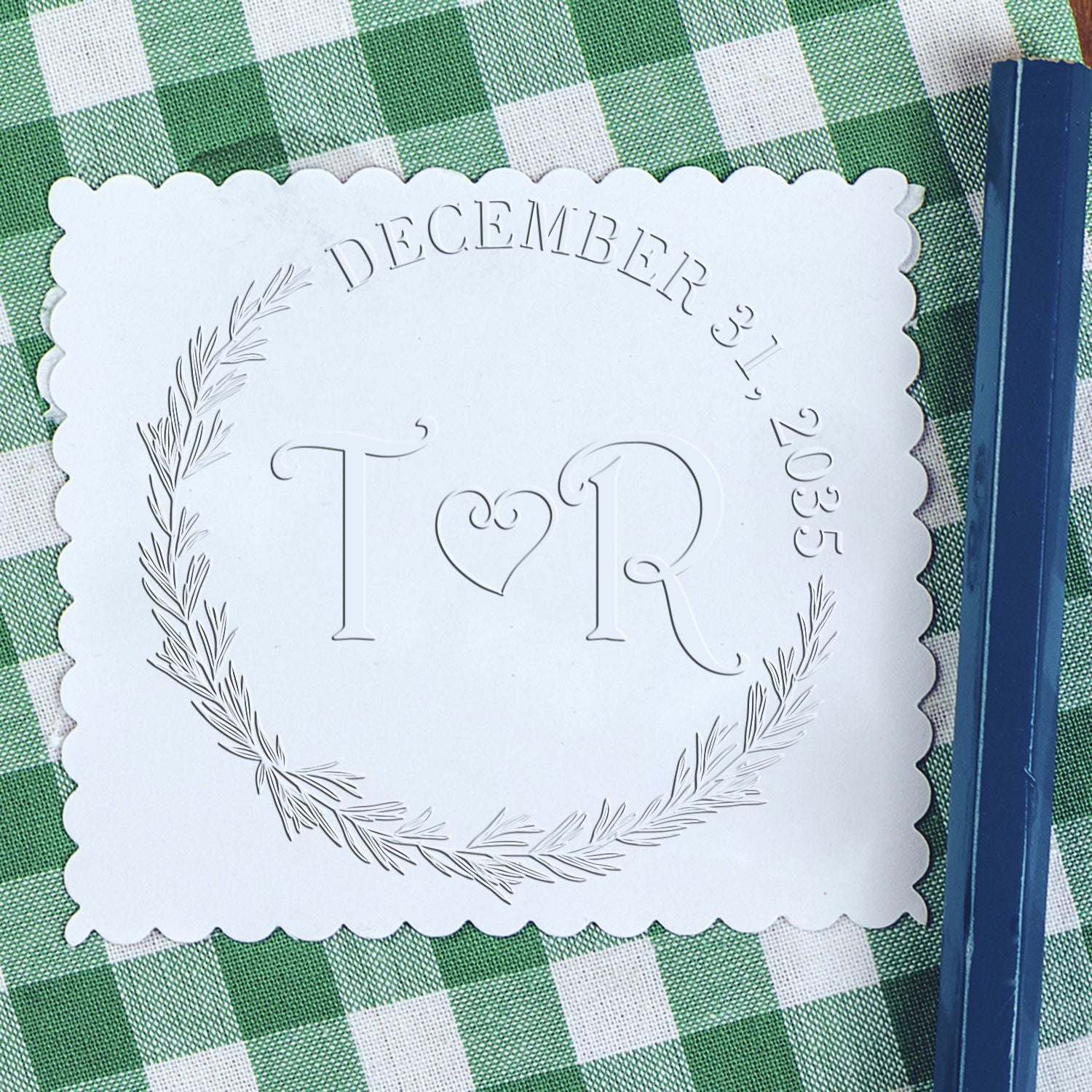 White scalloped custom stamp and seal with T?R monogram, December 31, 2035, on green gingham with blue pen.