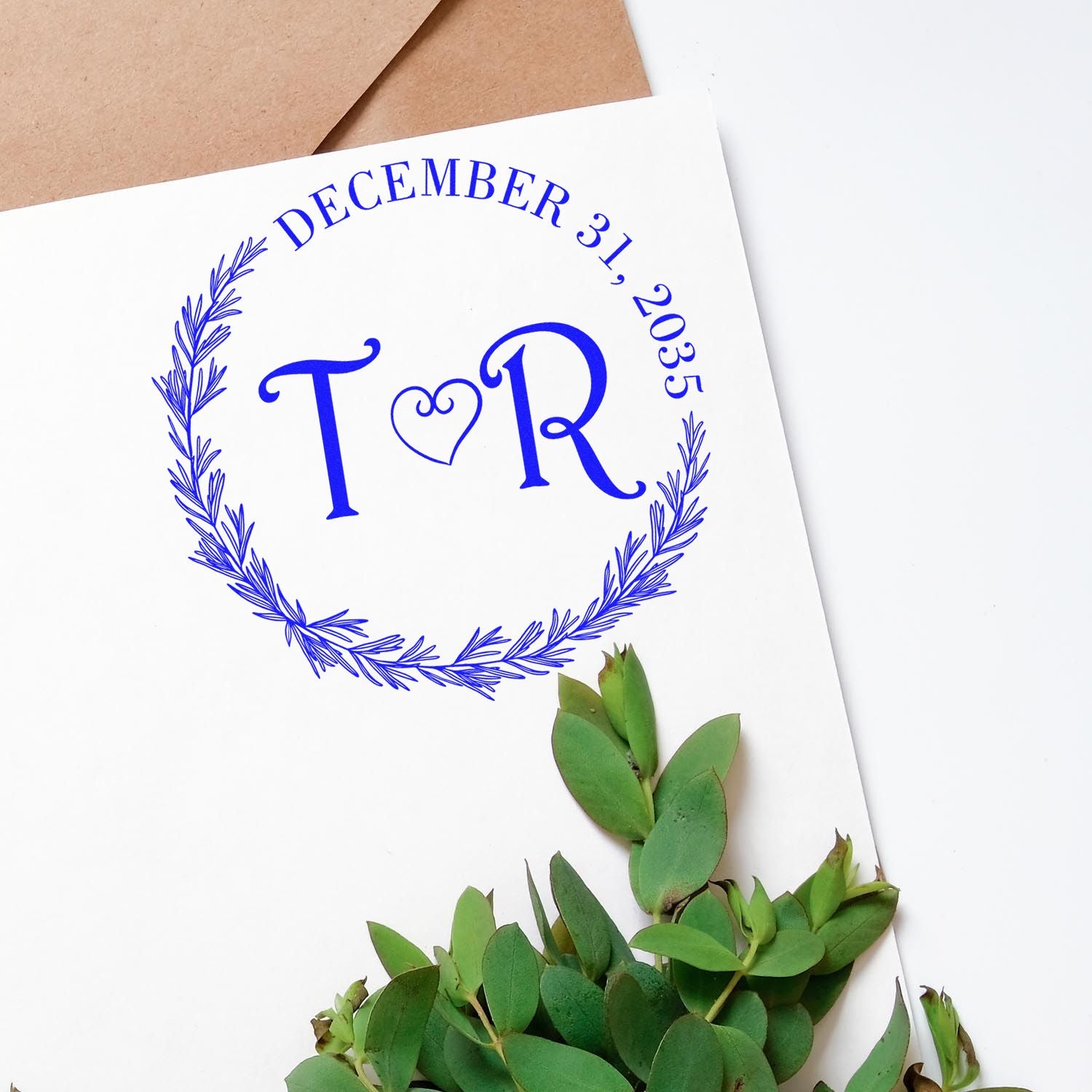 Blue custom stamp and seal design with T&R monogram, heart, and December 31, 2035 wreath on white card
