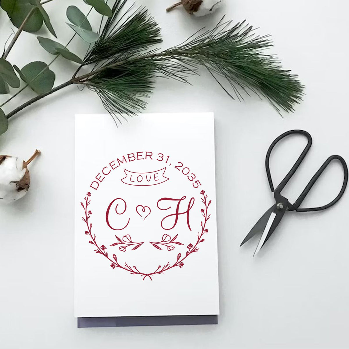 Burgundy custom wedding stamp and seal with initials C H, date December 31, 2035, and love banner on white card.