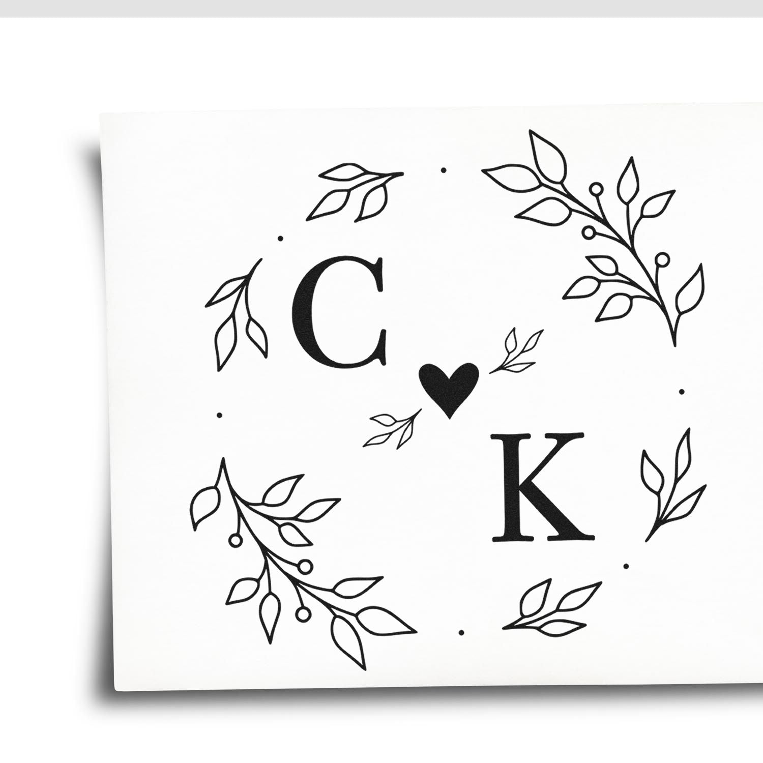 Black C?K monogram with leafy botanical wreath on a white custom stamp and seal design