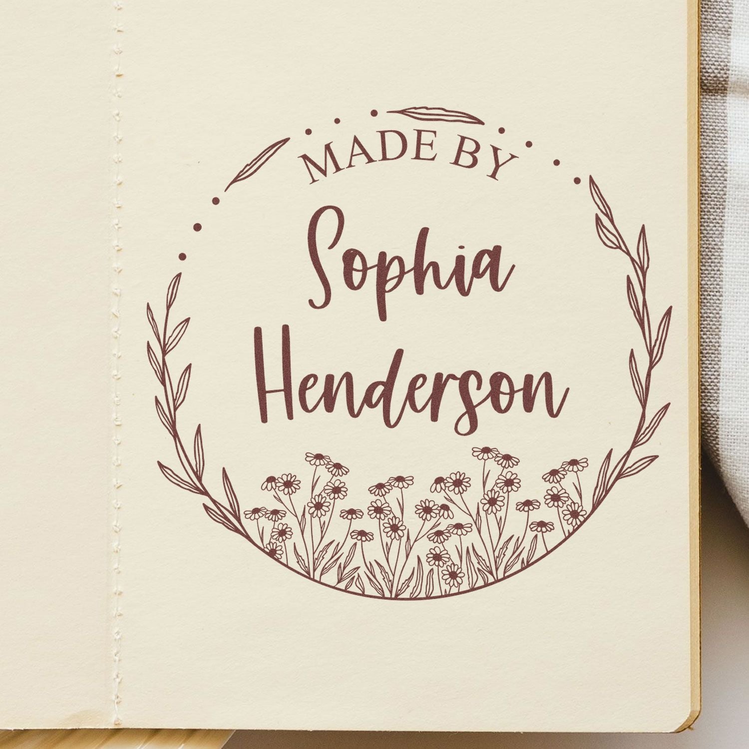 Custom burgundy stamp seal reading Made by Sophia Henderson with floral wreath on cream paper.