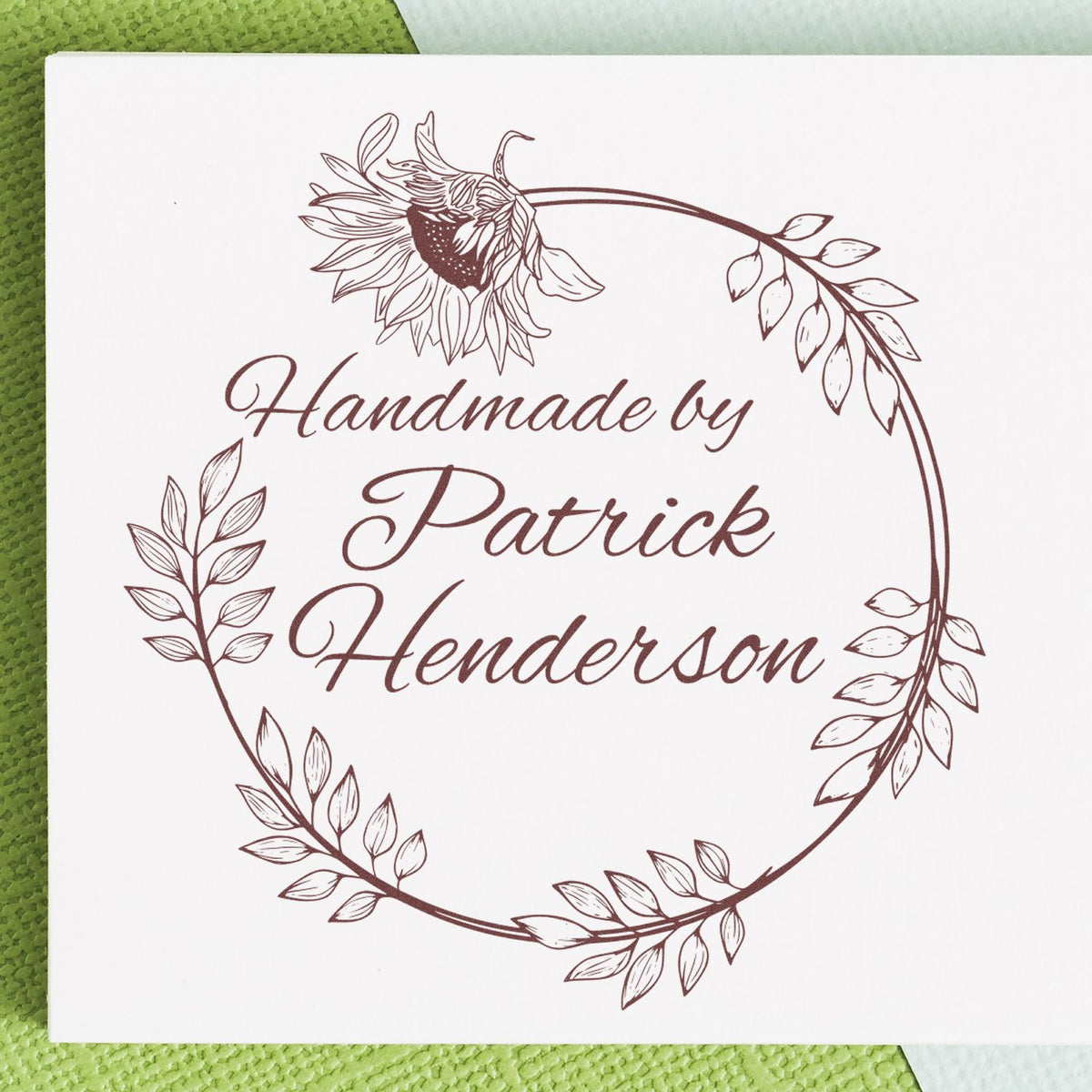 Brown floral wreath stamp reading Handmade by Patrick Henderson on white paper, custom seal design