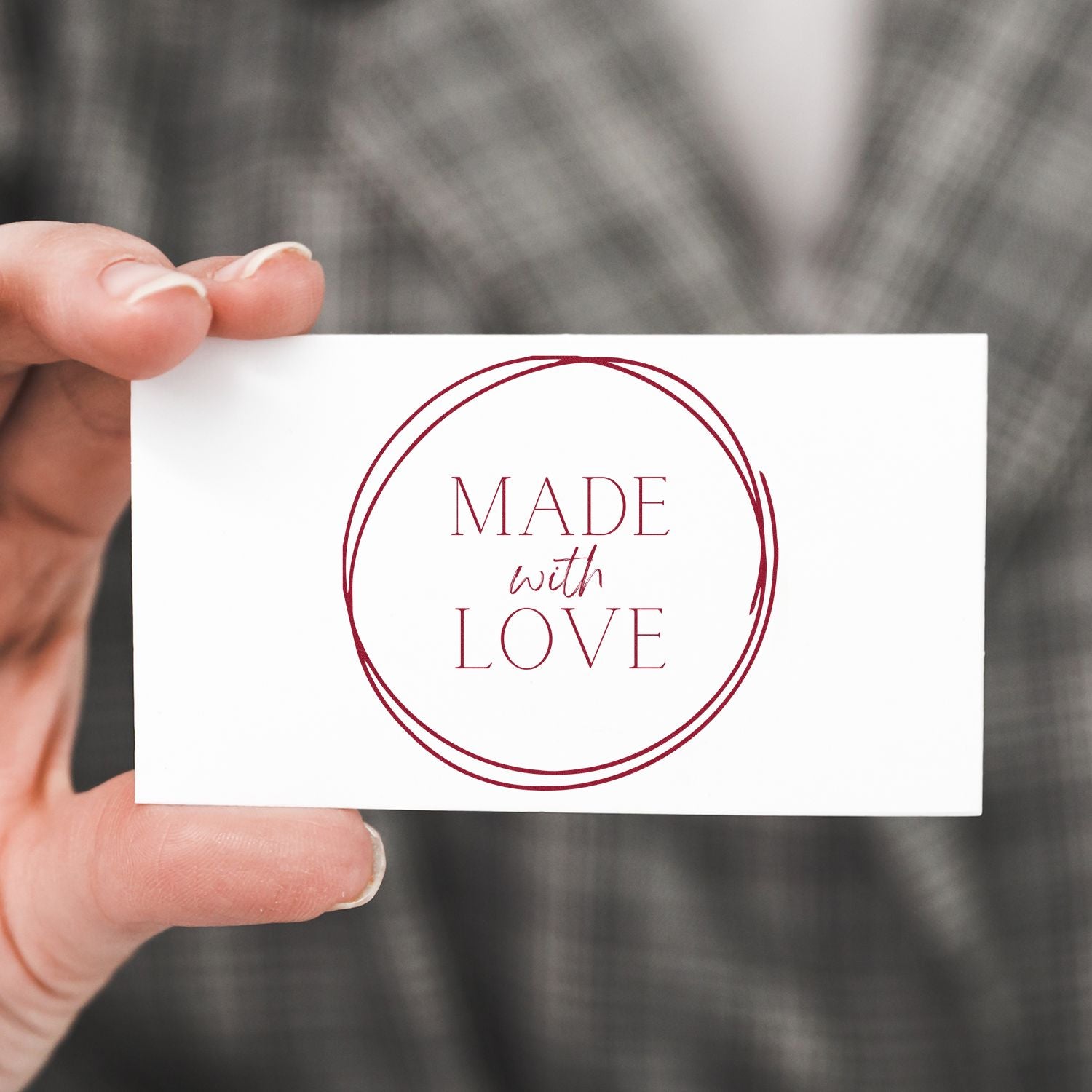Hand holding white card with burgundy circular stamp seal reading Made with Love.