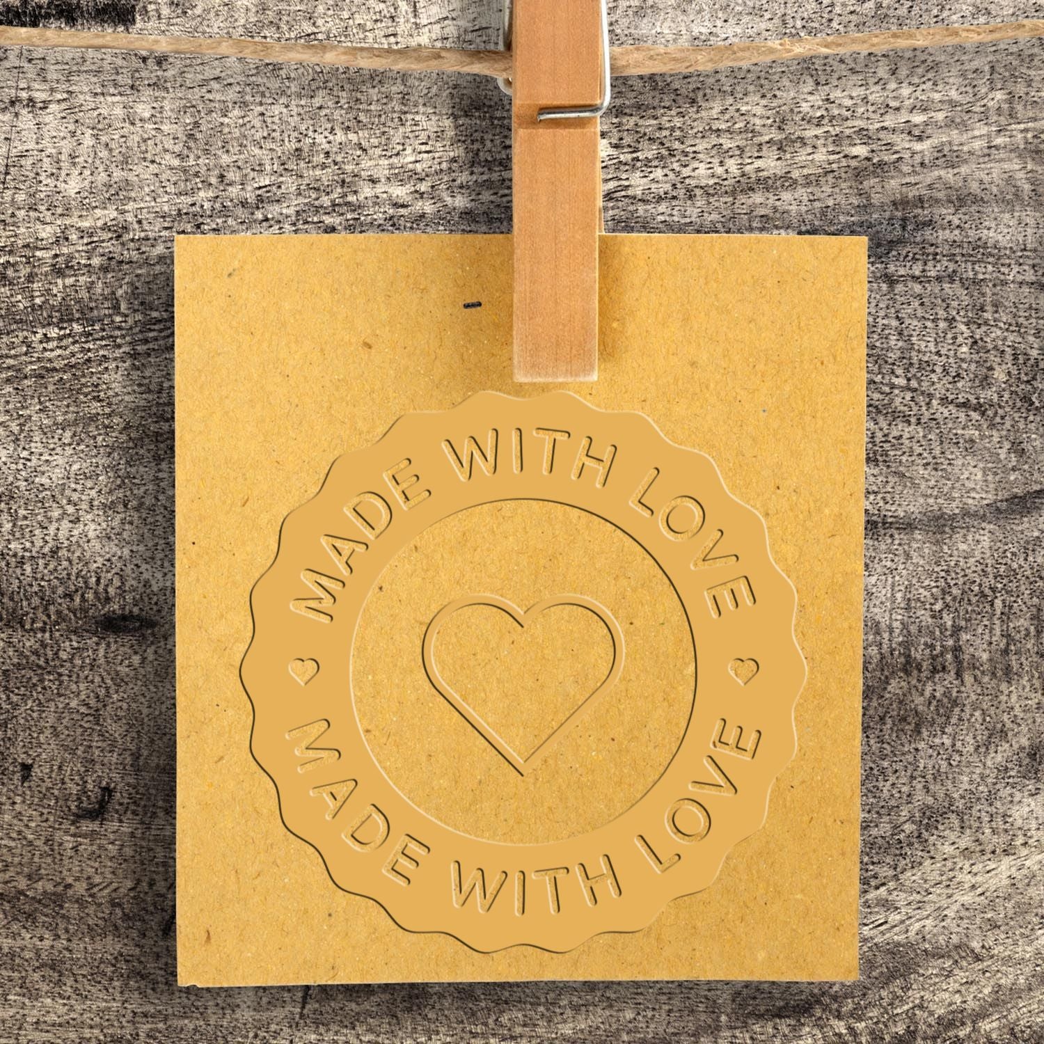 Kraft paper hang tag with gold embossed heart seal stamp reading Made with Love and a wooden clip.