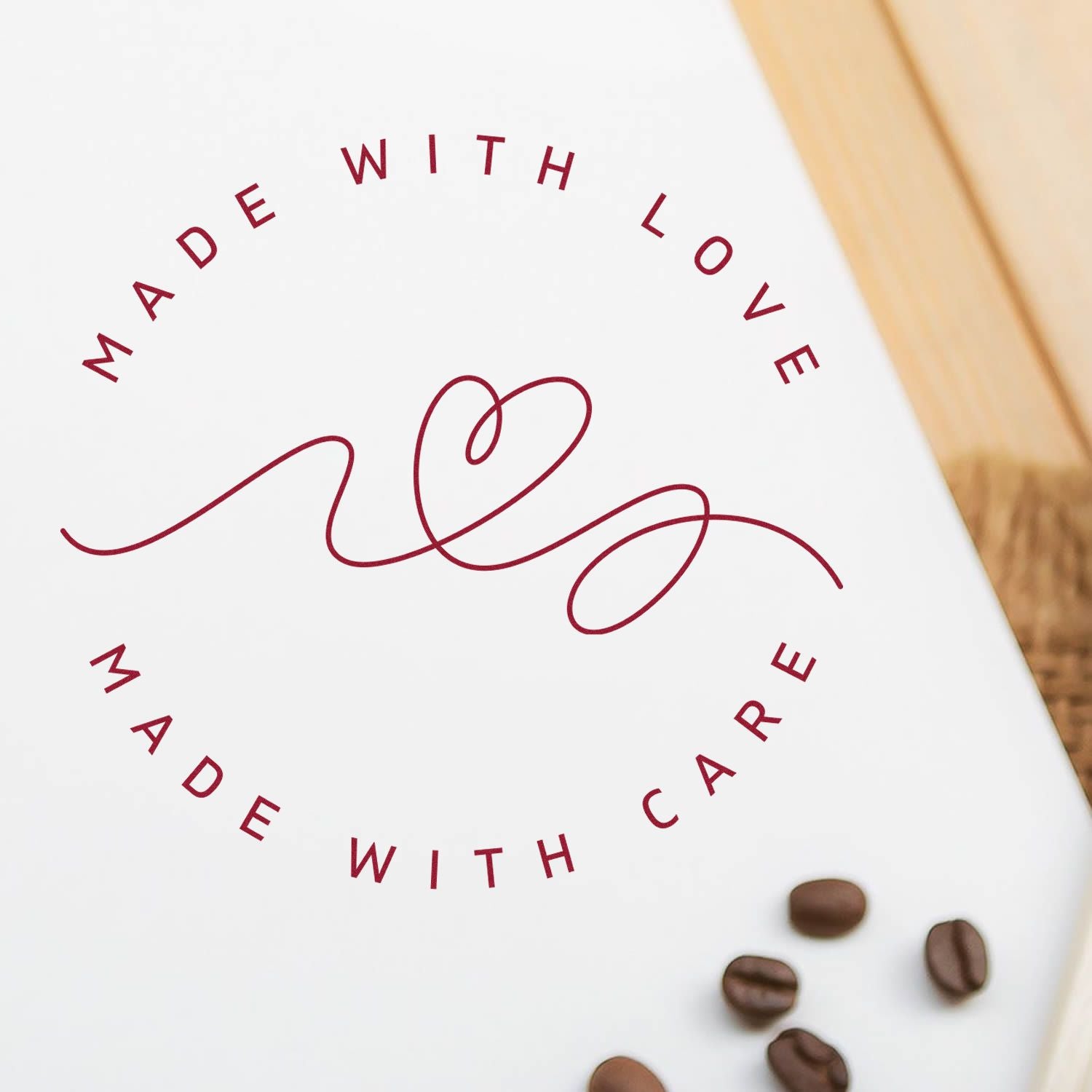 White stamp seal design with burgundy Made with Love, Made with Care text, heart line art, and coffee beans.