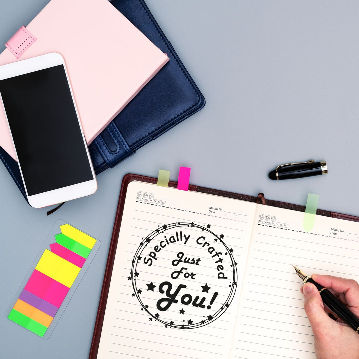 Black custom seal stamp reading Specially Crafted Just For You! in open planner, with fountain pen and pastel tabs.